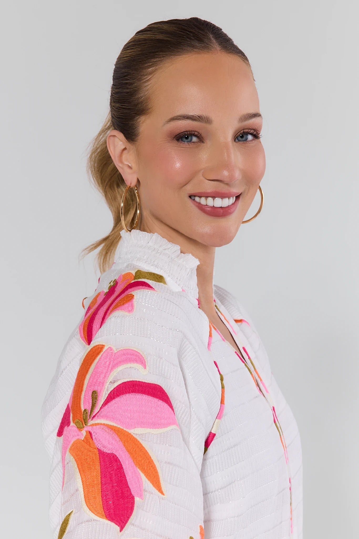 Woman wearing a white floral blouse against a plain background