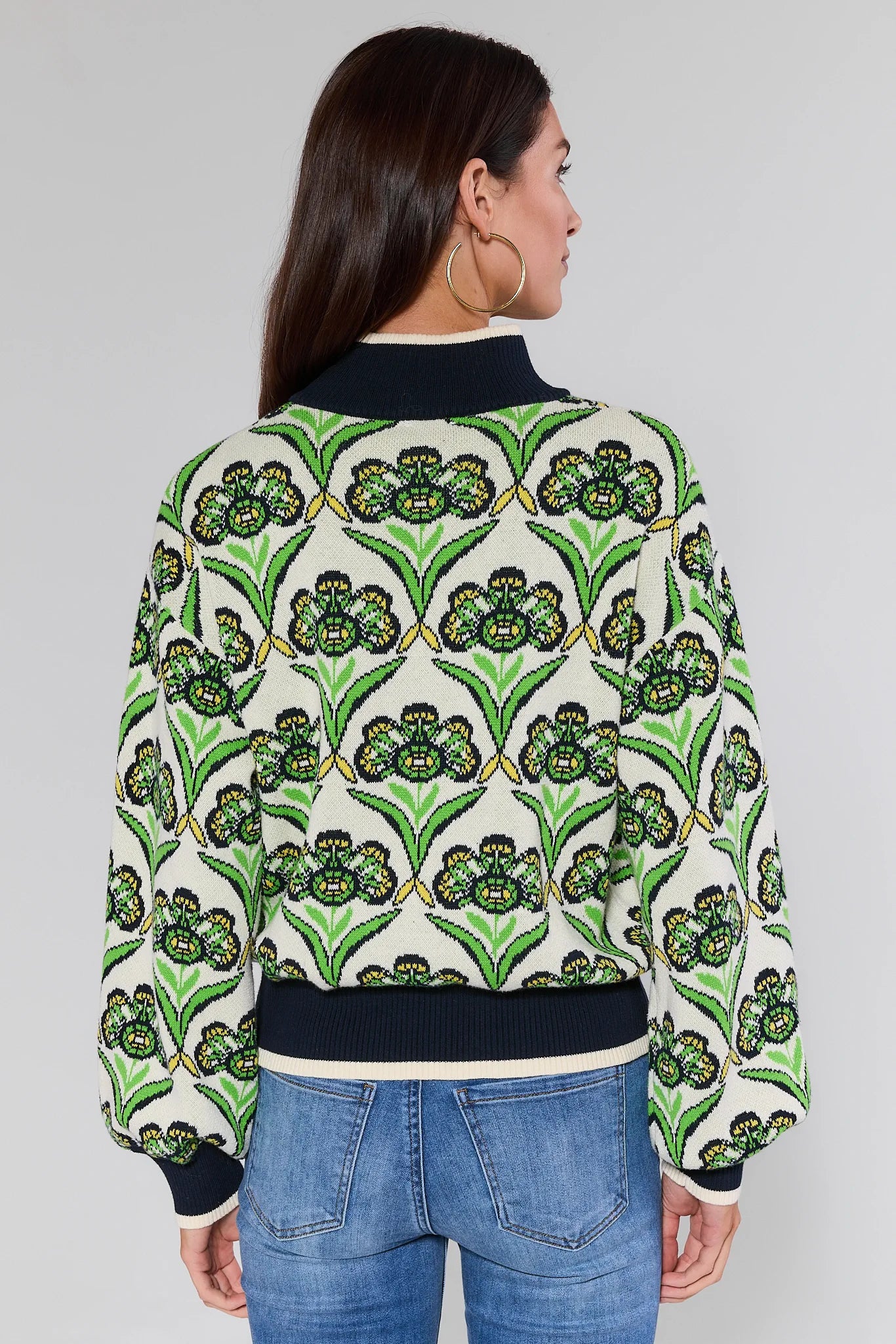 Woman wearing a Andrea Green Half Zip Sweater with green floral design on a plain background