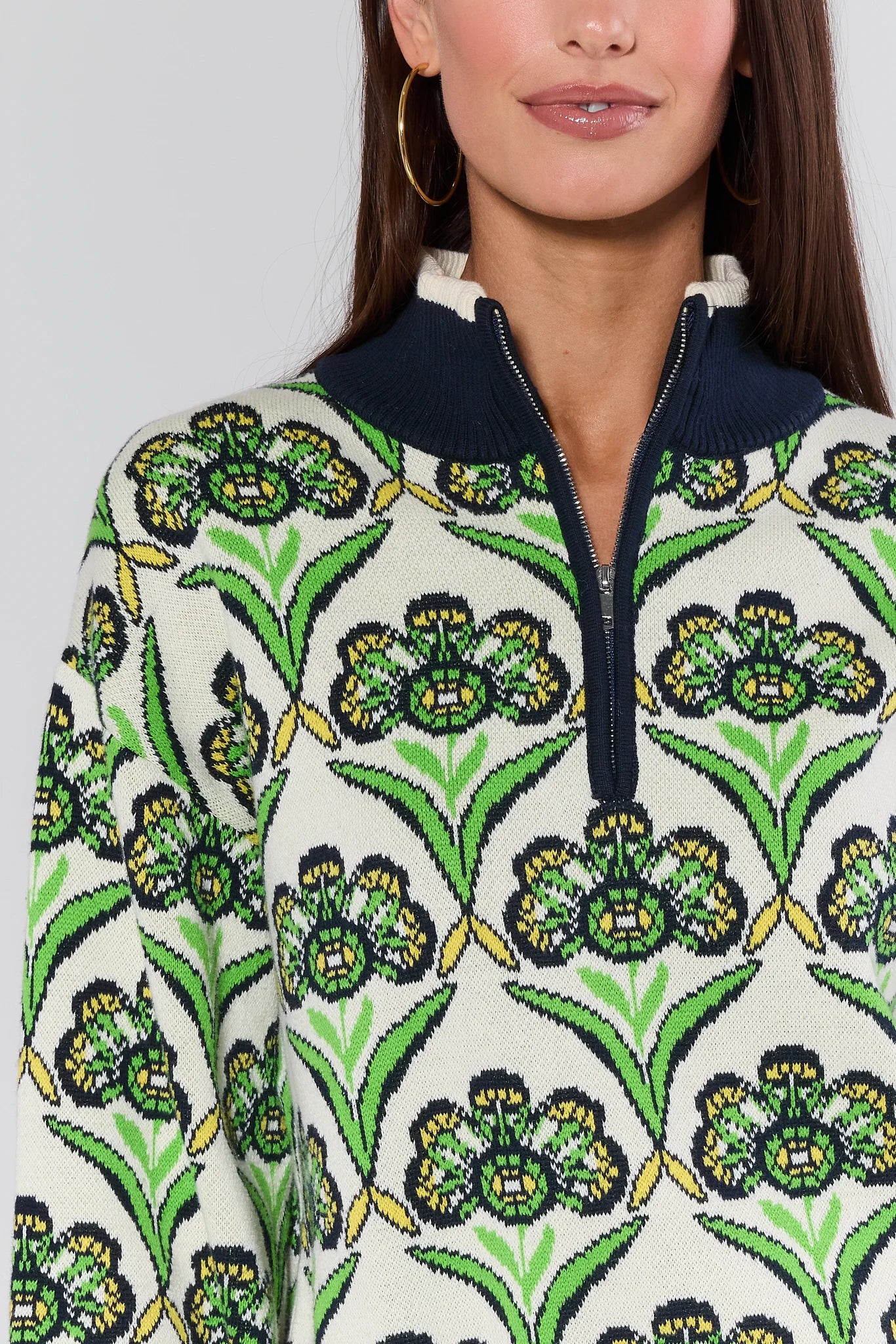 Woman wearing a Andrea Green Half Zip Sweater with green floral design on a plain background