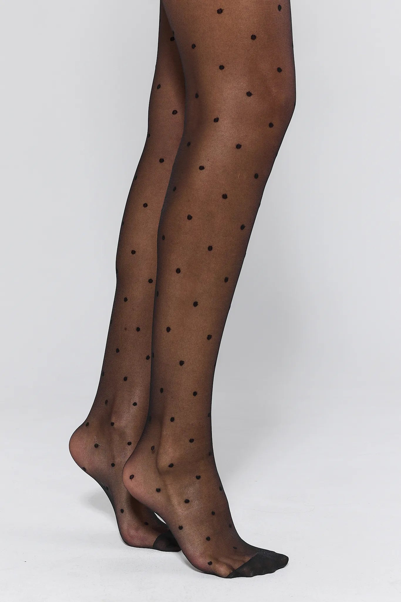 Penelope Black Polka Dot Tights worn by a person on a white background