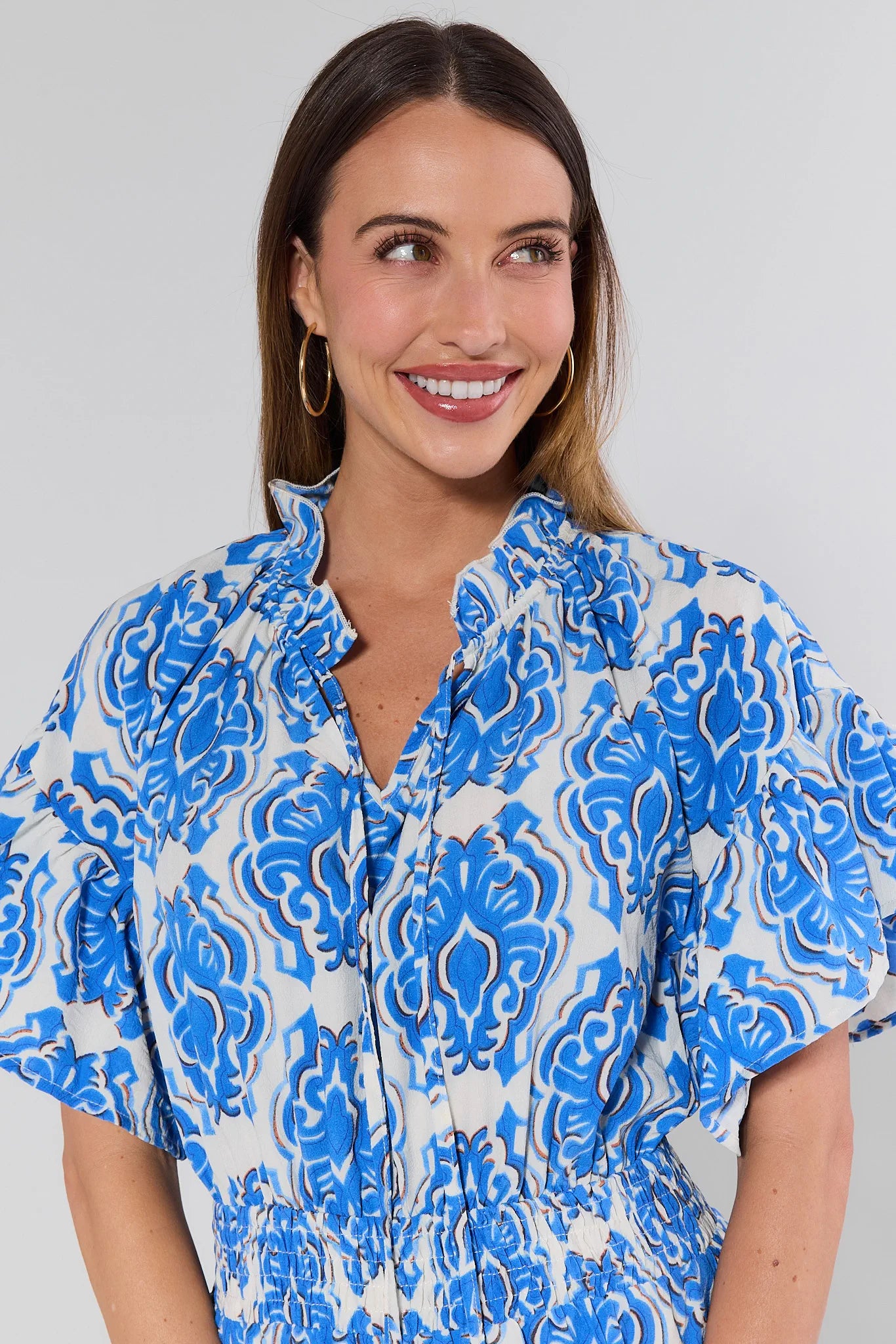 Woman wearing a blue and white patterned dress against a gray background