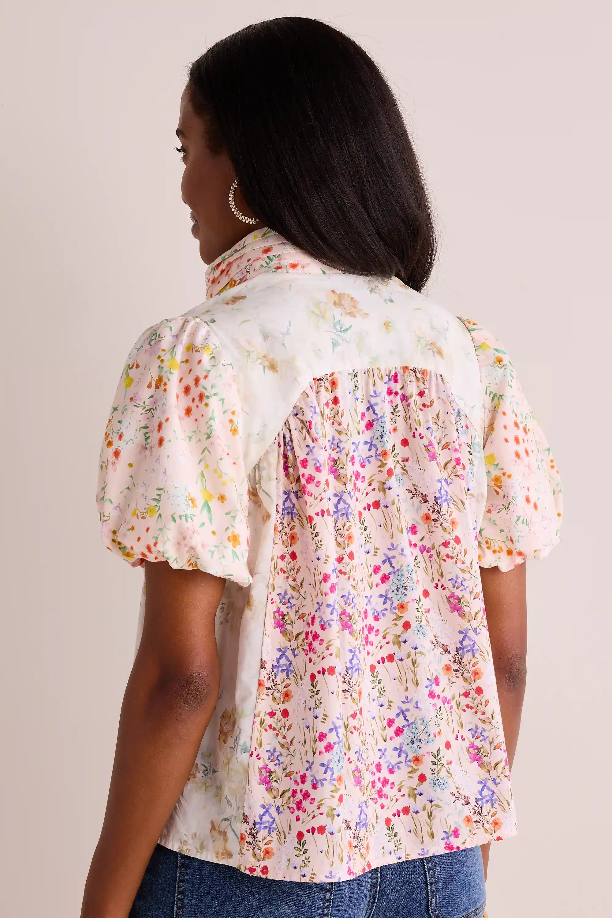 Woman in Margie Floral Print Puff Sleeve Top, showcasing its mixed floral design, puff sleeves, and relaxed fit, styled with jeans and gold hoop earring.
