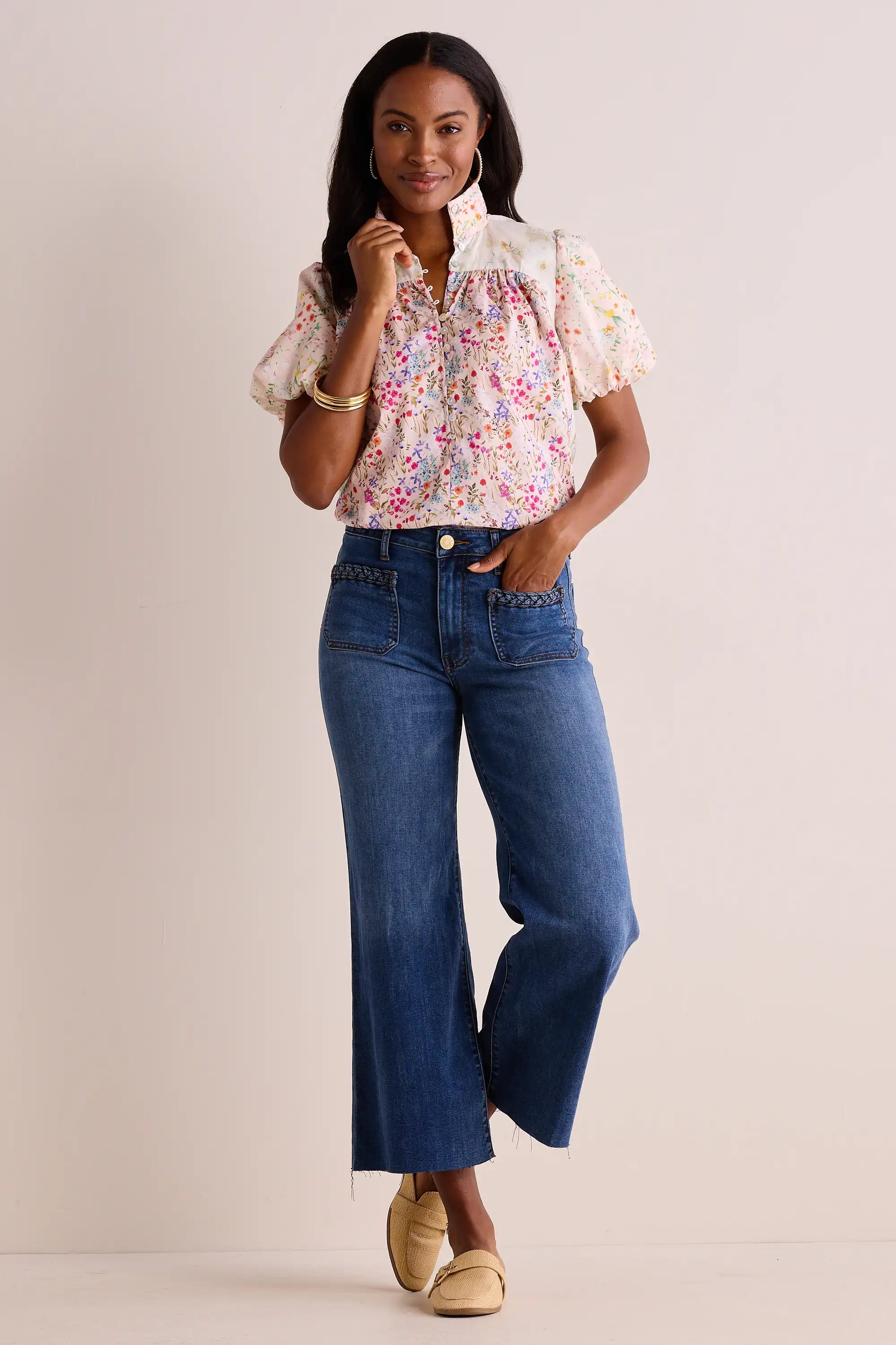 Model in Margie Floral Print Puff Sleeve Top, featuring a ruffled collar and button-front, paired with wide-leg denim trousers and loafers, accessorized with hoop earrings.