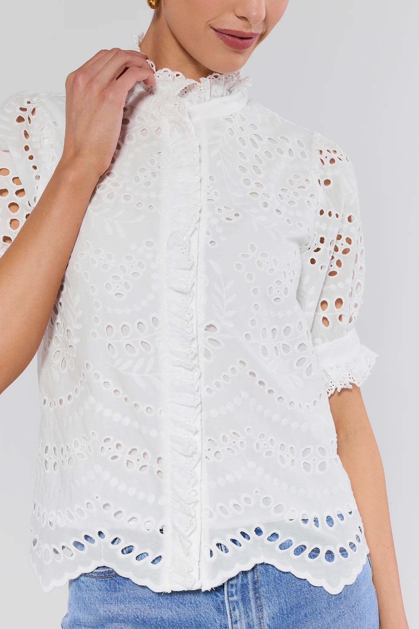White lace blouse with blue accents worn by a person on a white background
