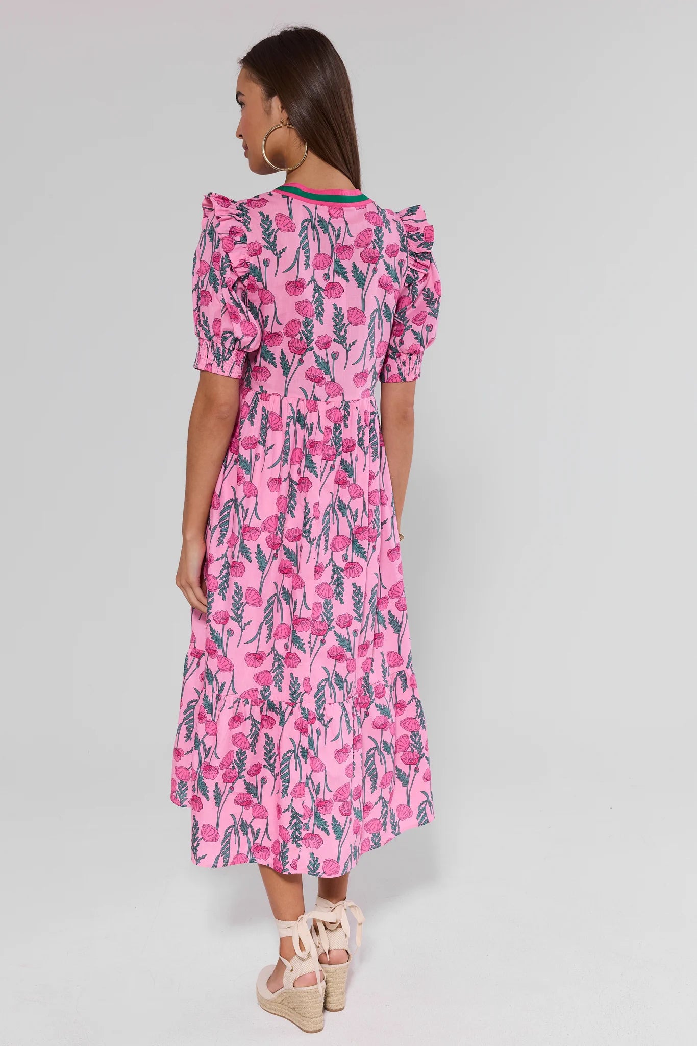 Woman standing wearing a pink floral dress on a gray background