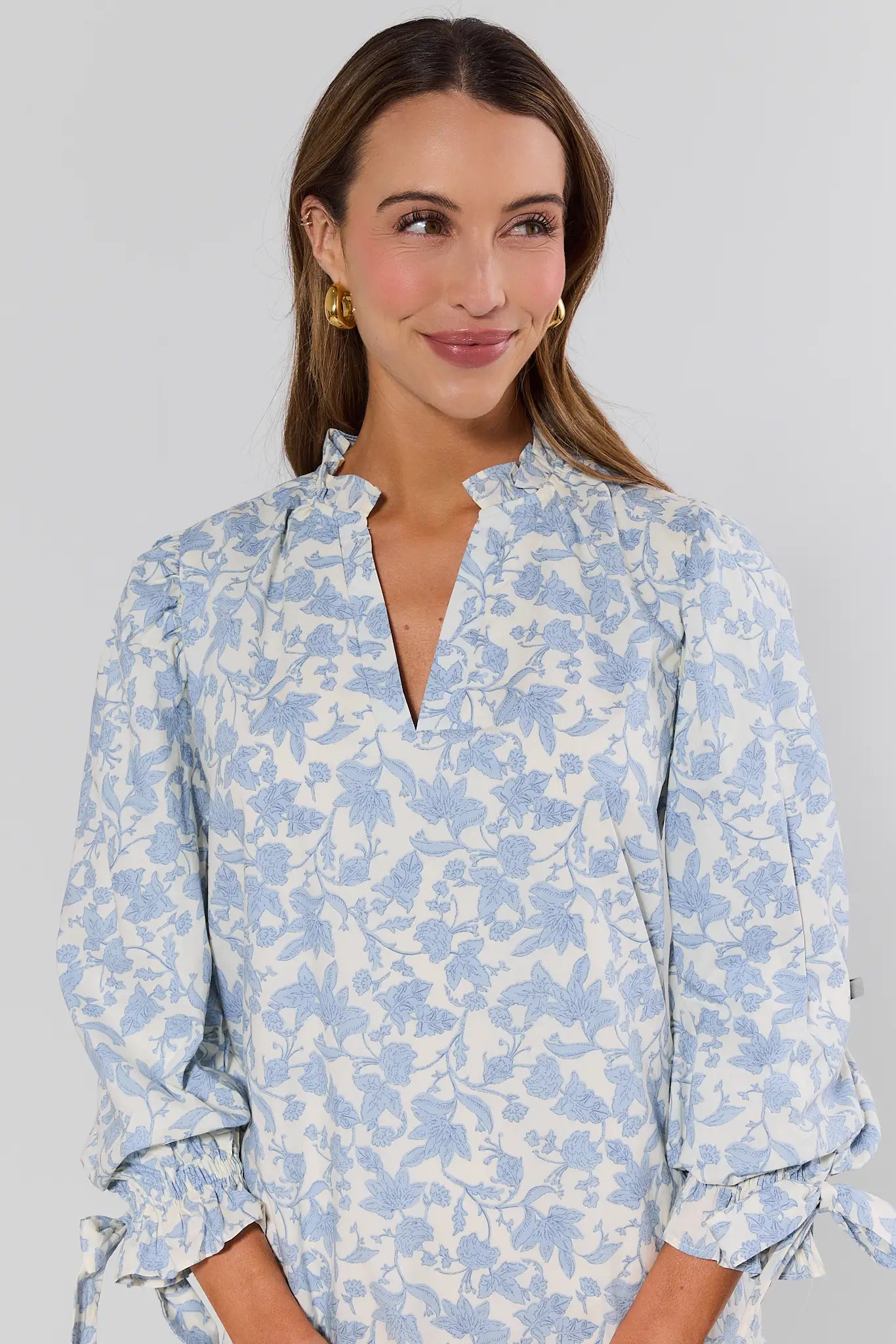 close up Woman wearing a blue floral blouse against a gray background