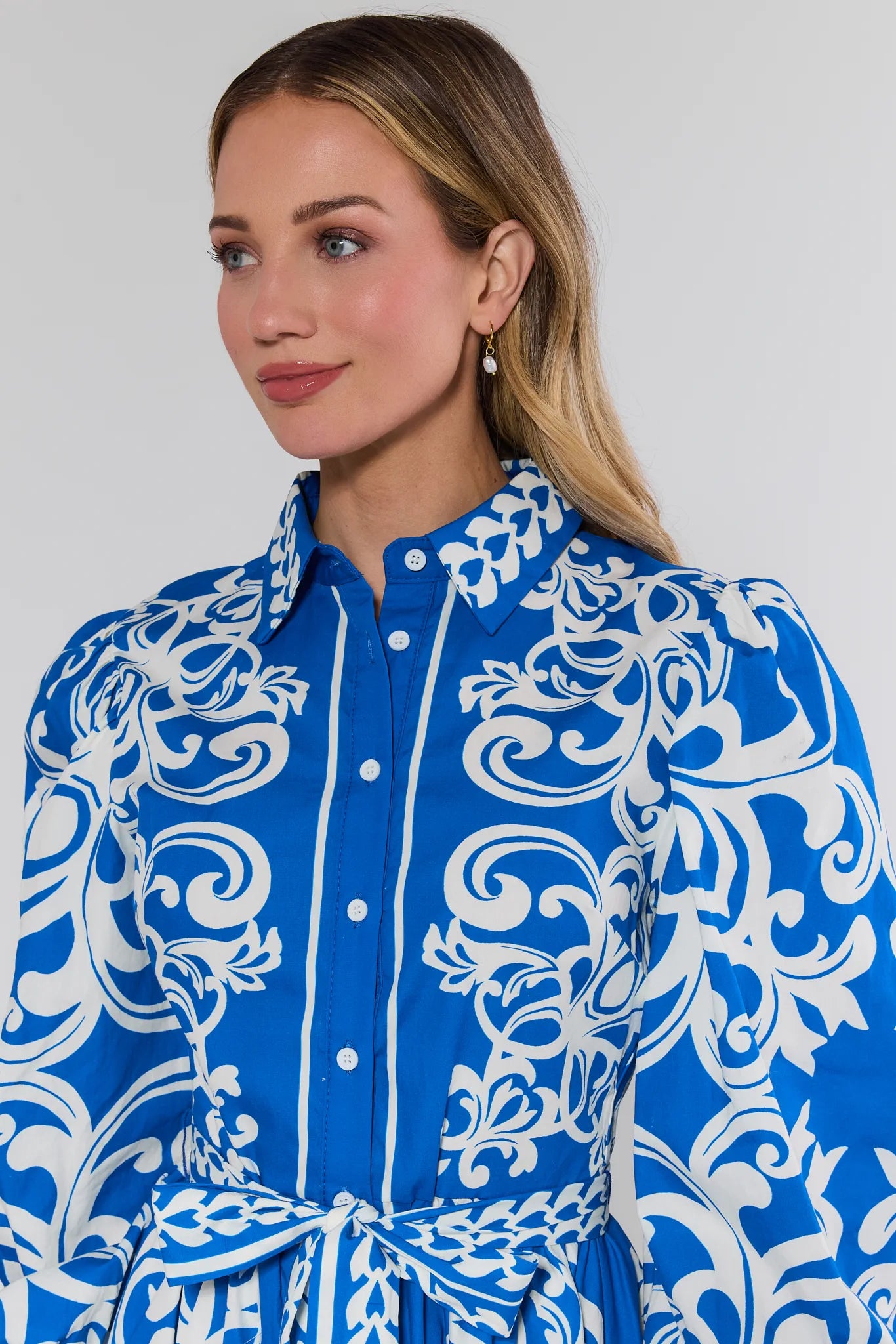 Woman wearing a blue and white patterned dress against a plain background