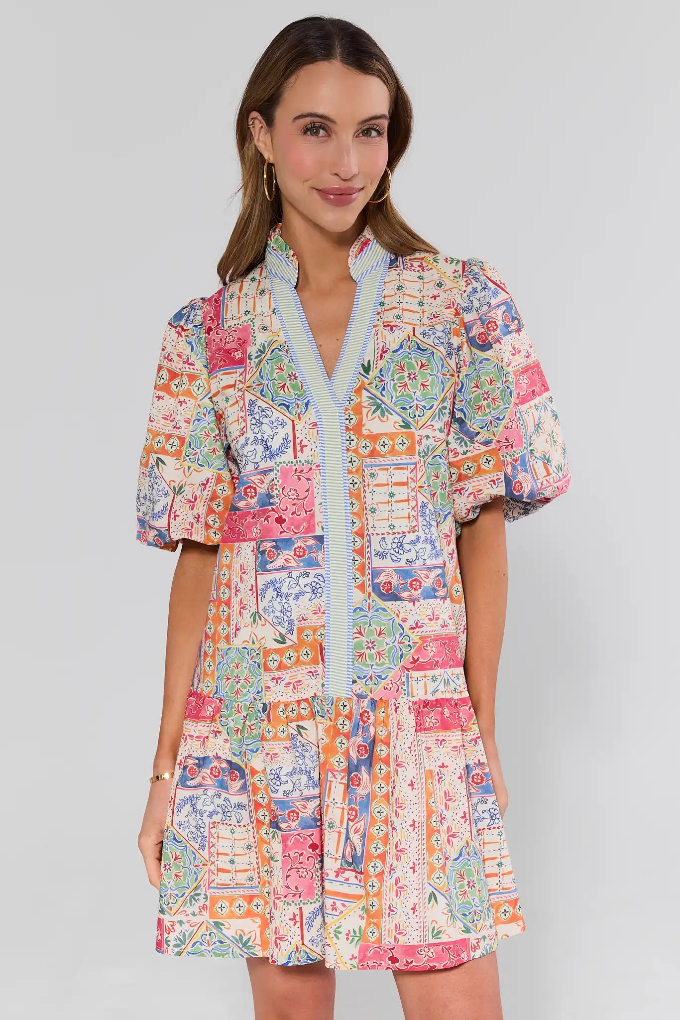 Woman wearing a colorful patterned olivia dress on a plain background