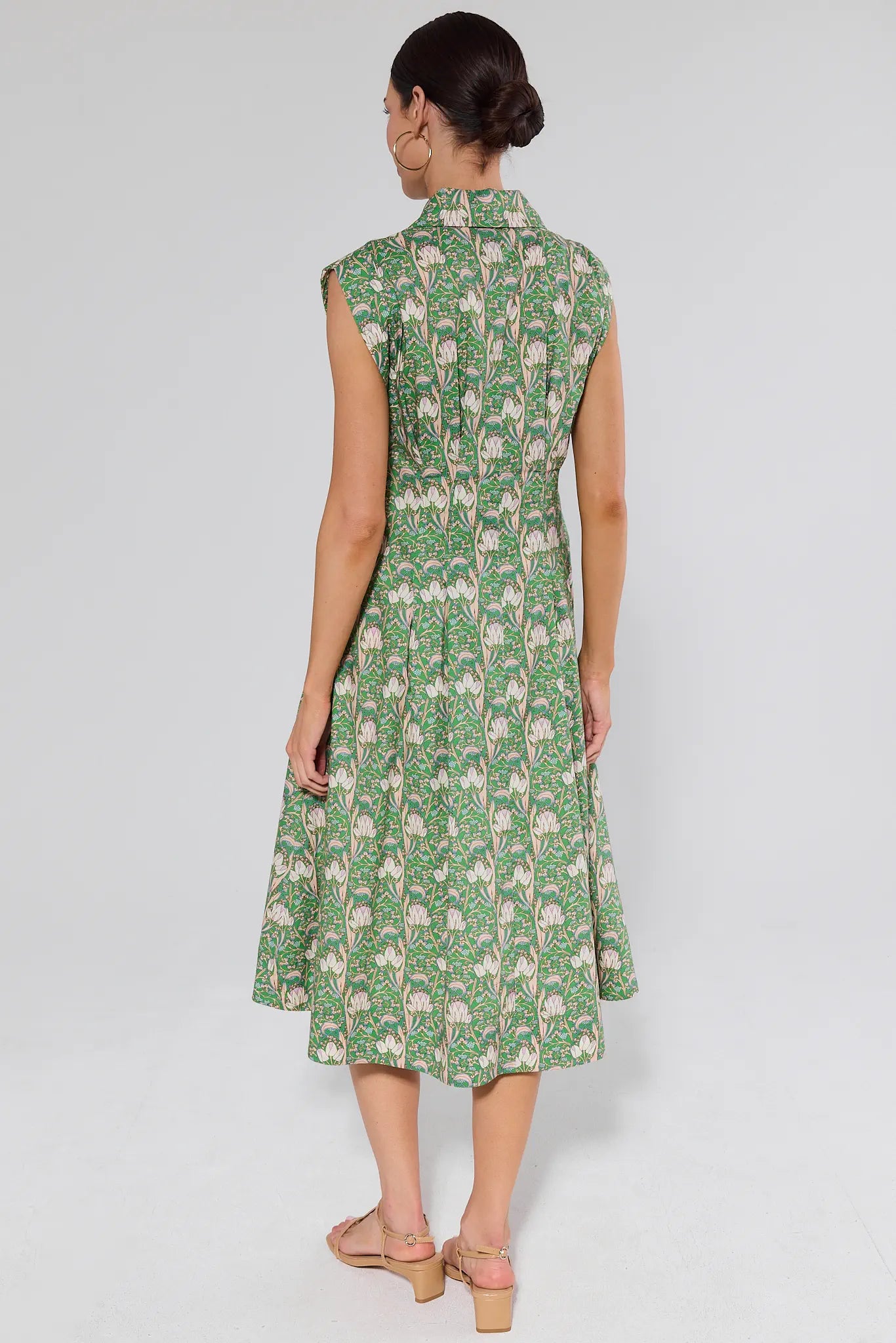 Woman backwards wearing a green patterned dress on a white background