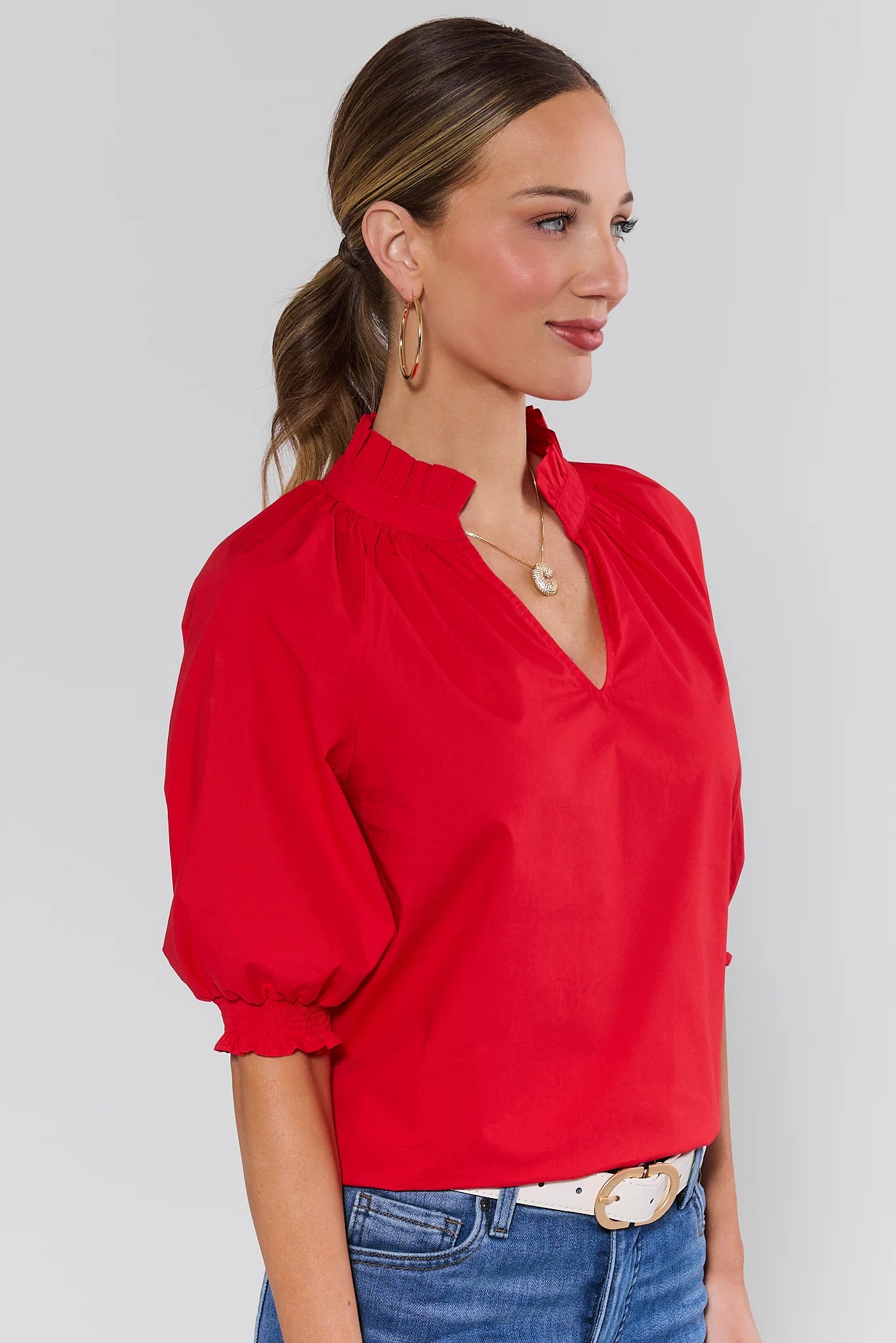 side shot Woman wearing a red blouse with a plain background