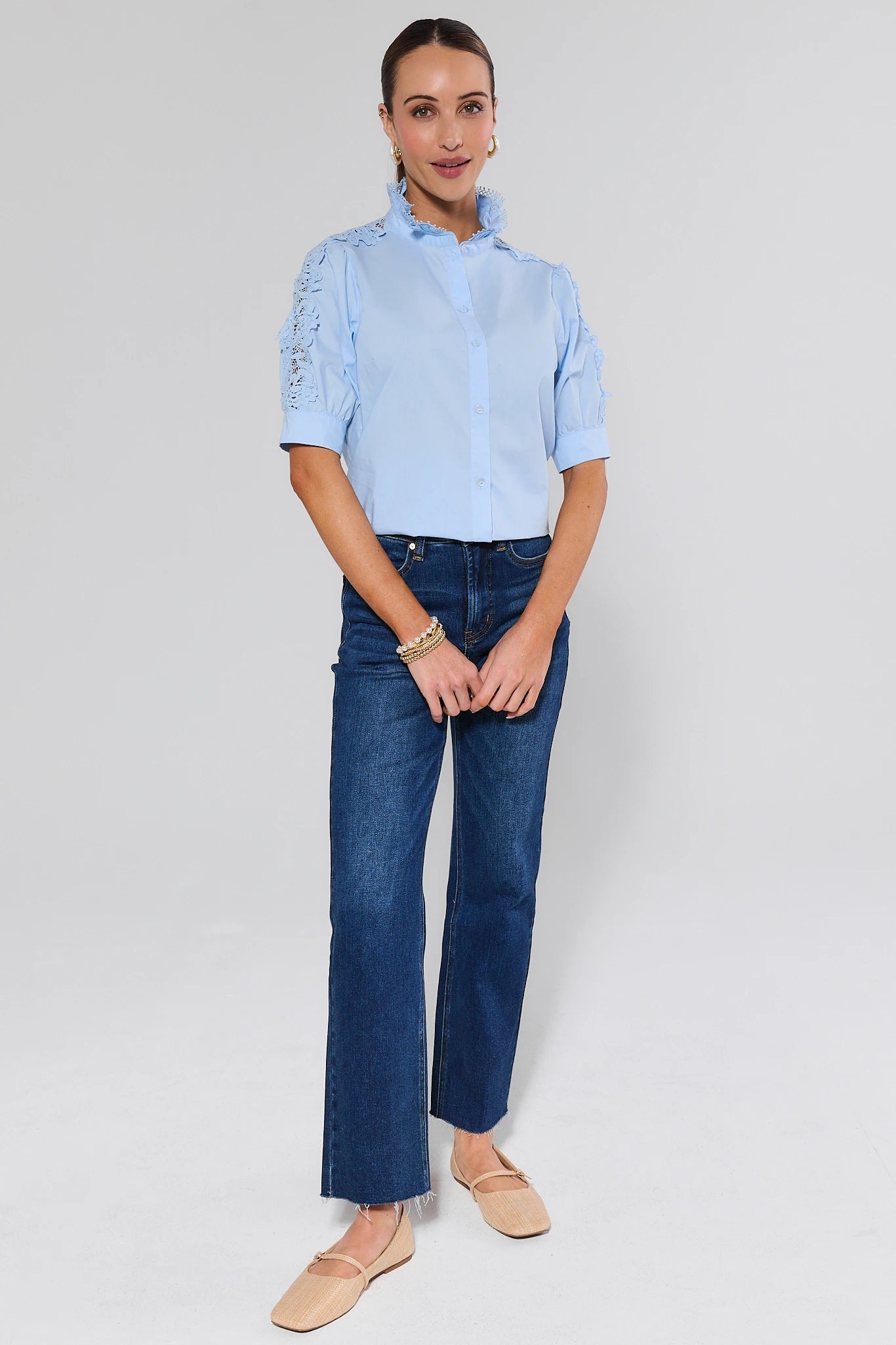 Woman wearing a light blue shirt and dark blue jeans on a white background