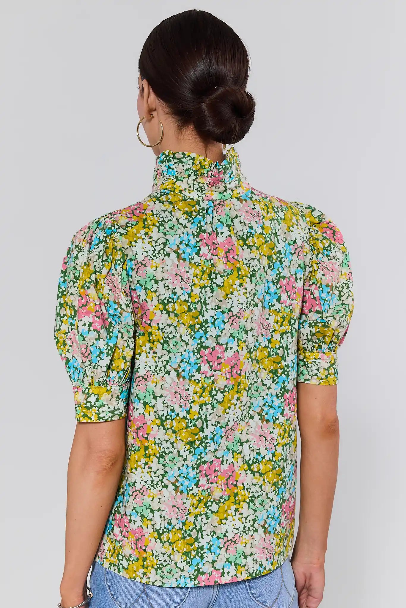 Woman standing wearing a floral patterned shirt against a plain background