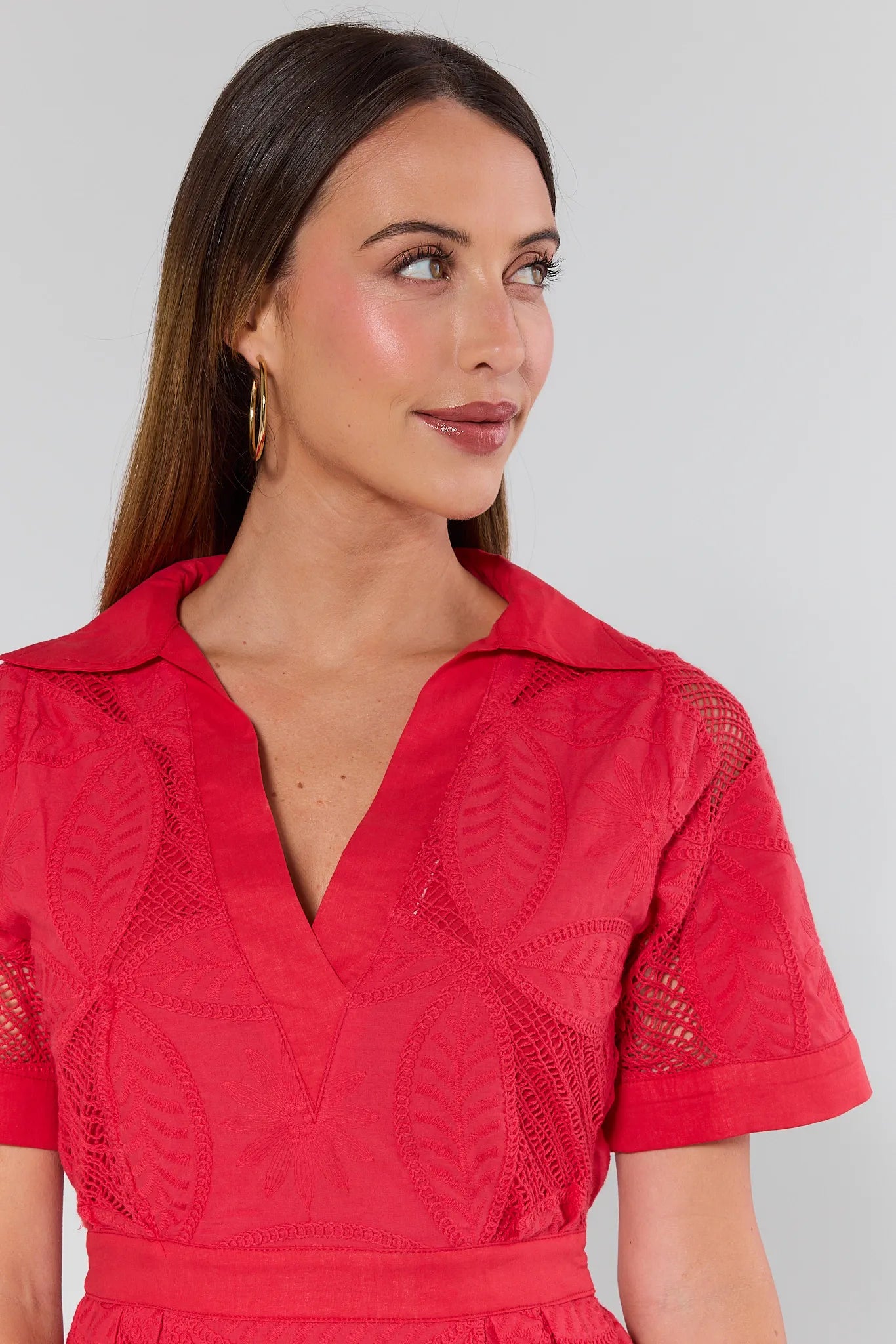 Woman wearing a red lace dress against a gray background