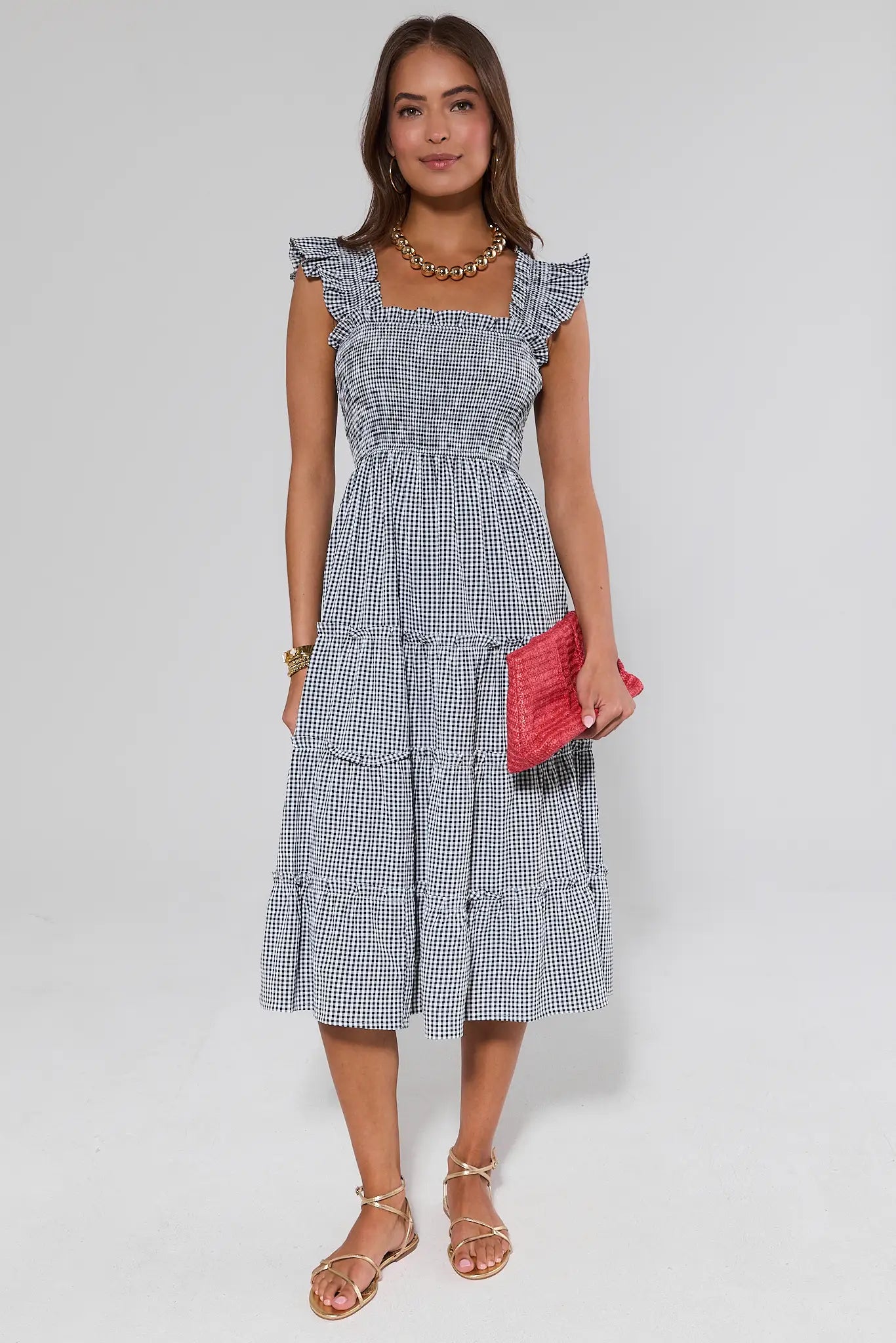 Woman wearing a alexandra checkered dress with ruffled sleeves against a plain background