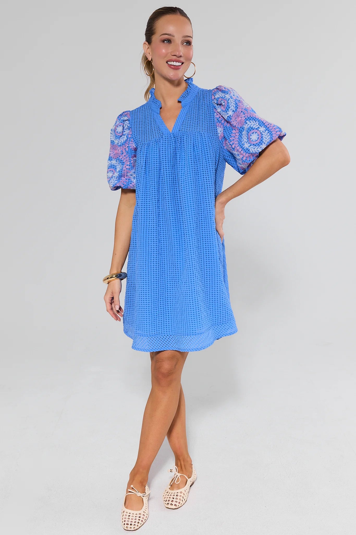 Woman wearing a blue dress with white patterns on a background