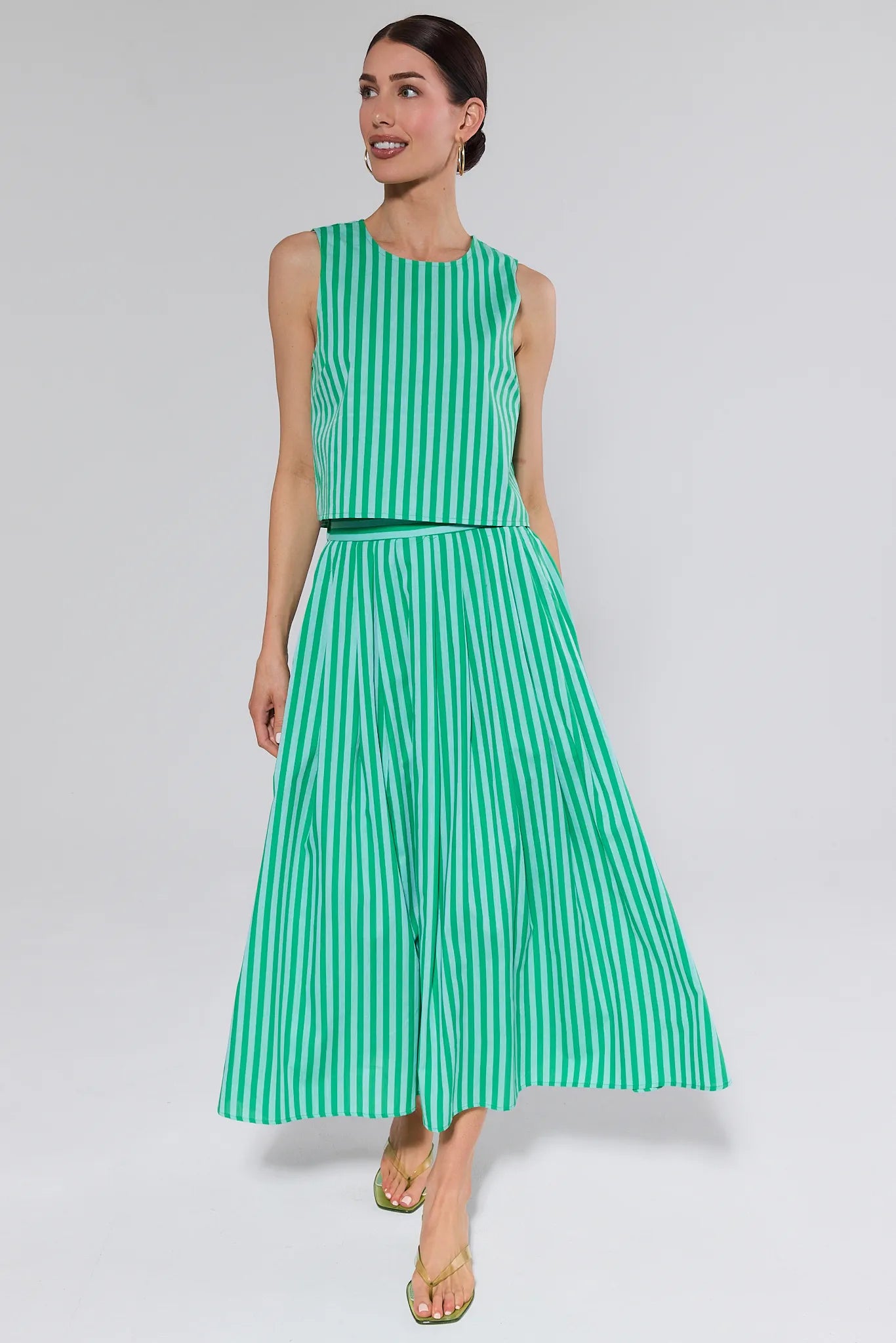 Woman wearing a green and white striped dress on a plain background