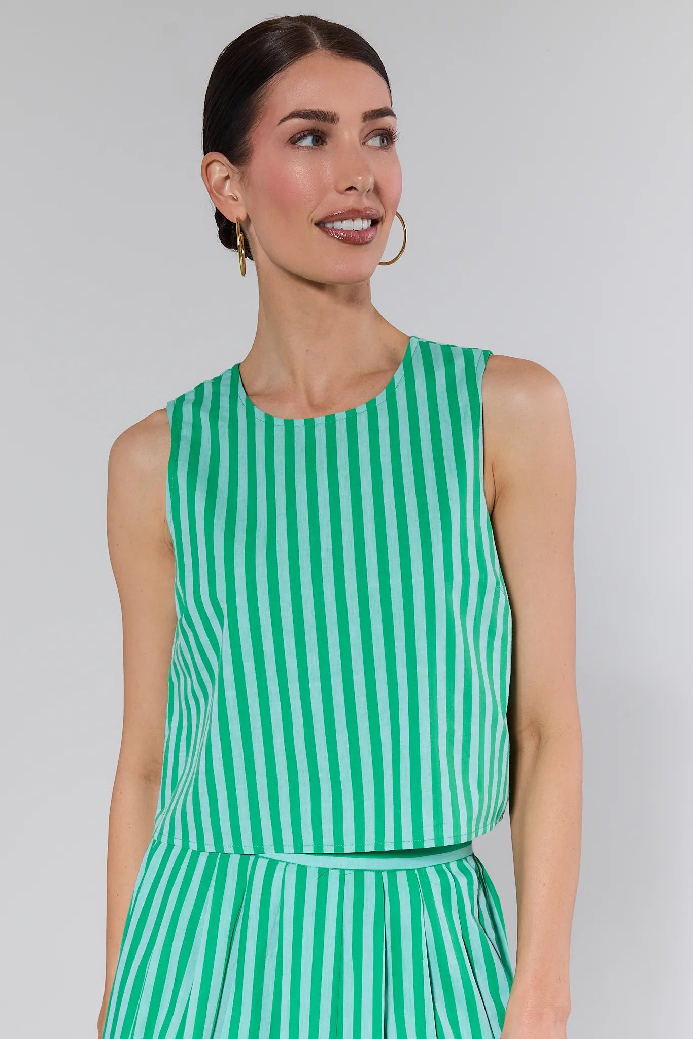 Woman wearing a green and white striped outfit against a plain background