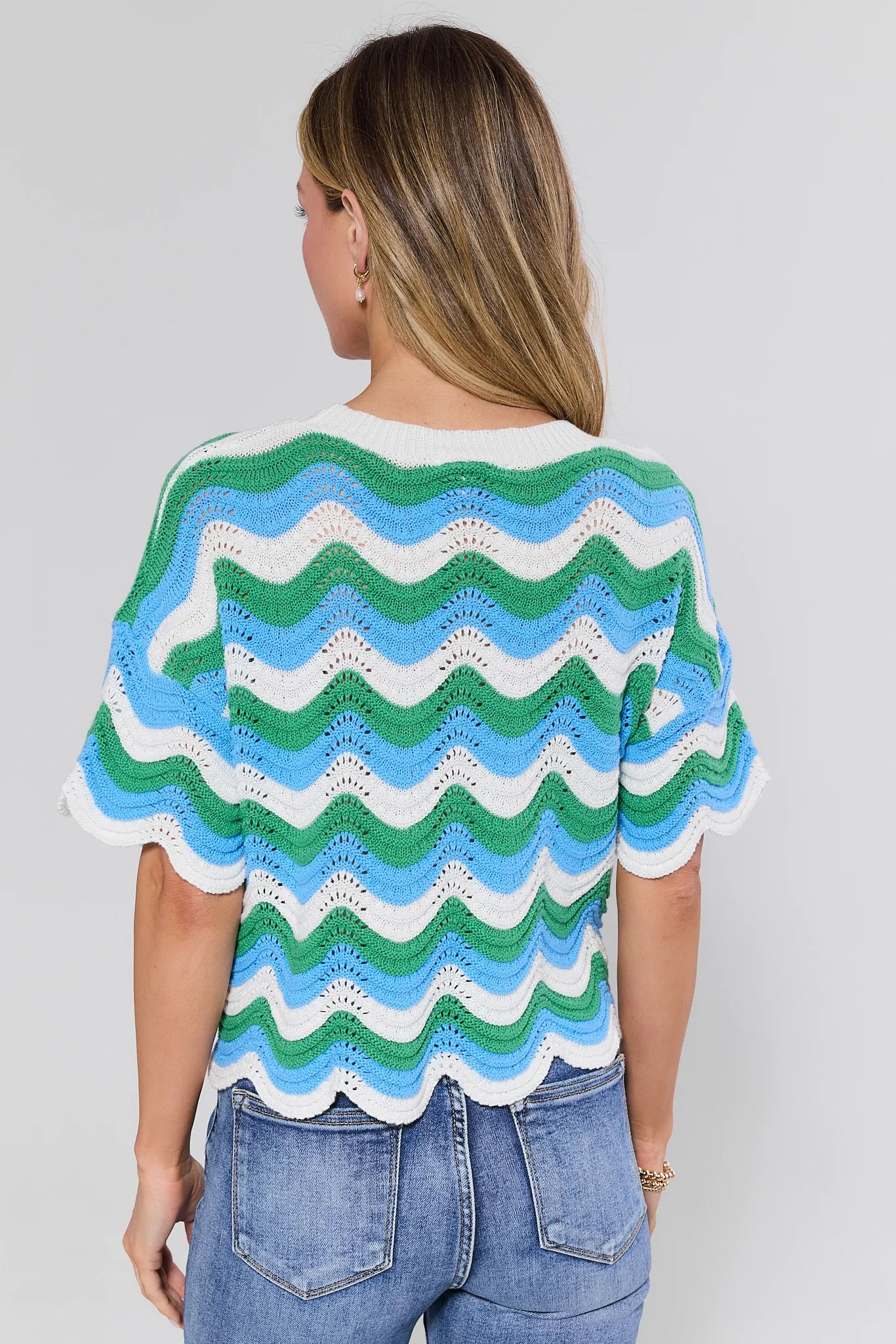 Woman wearing a colorful striped sweater against a plain background