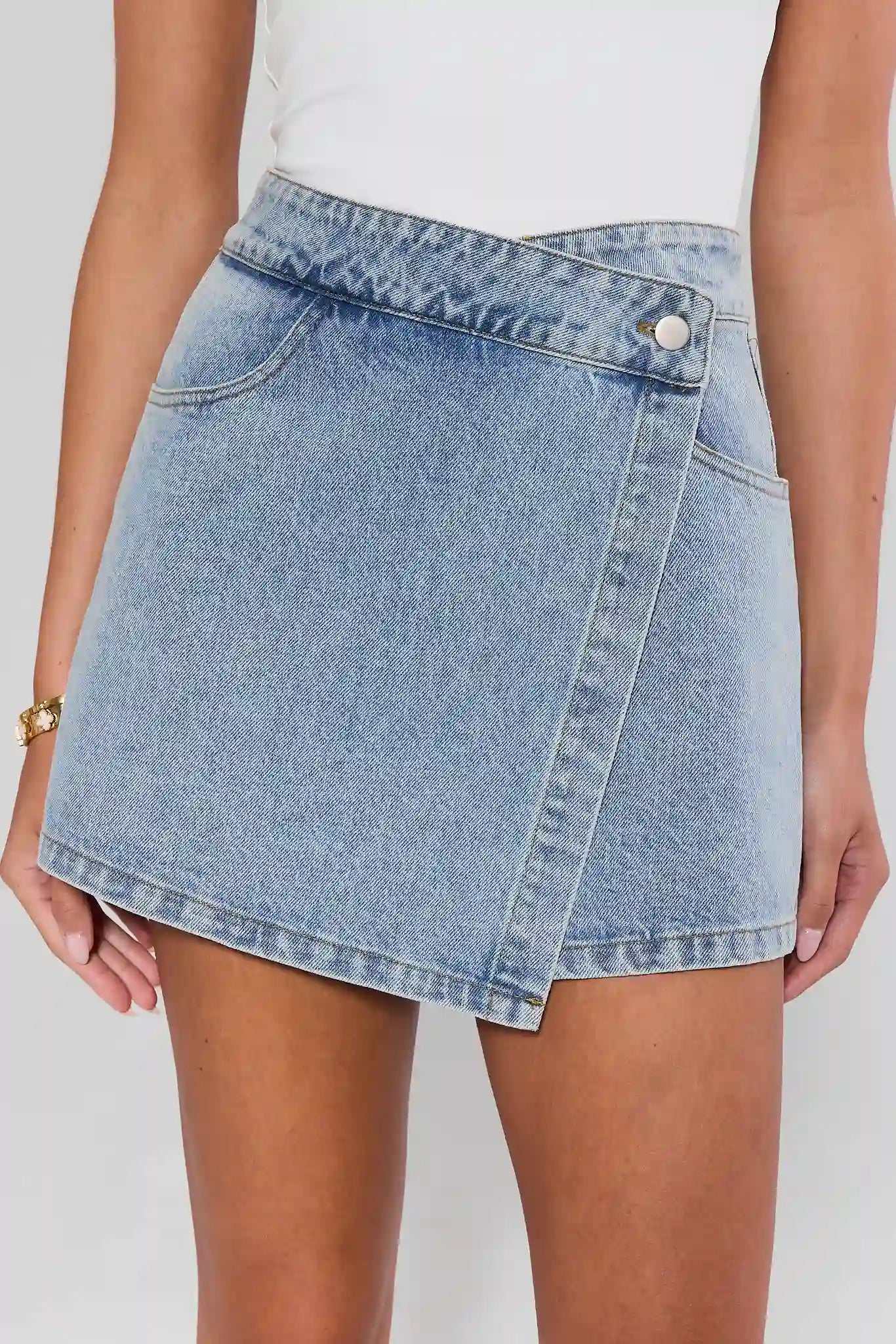 Light blue denim skirt worn by a person on a white background