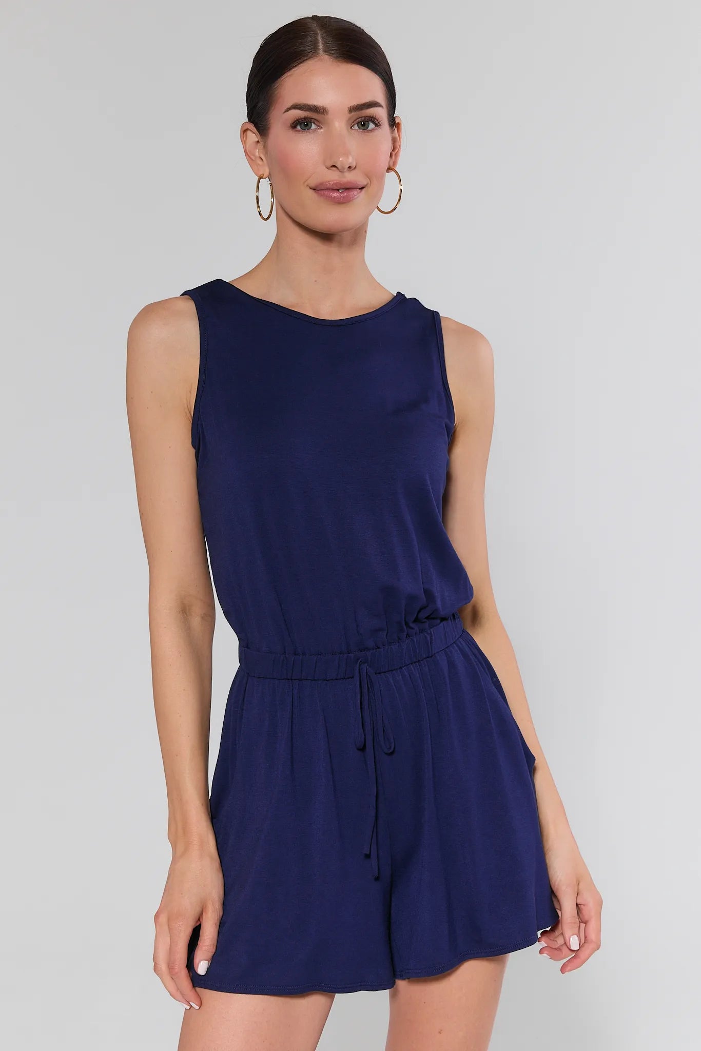 Woman wearing a navy blue romper against a plain background