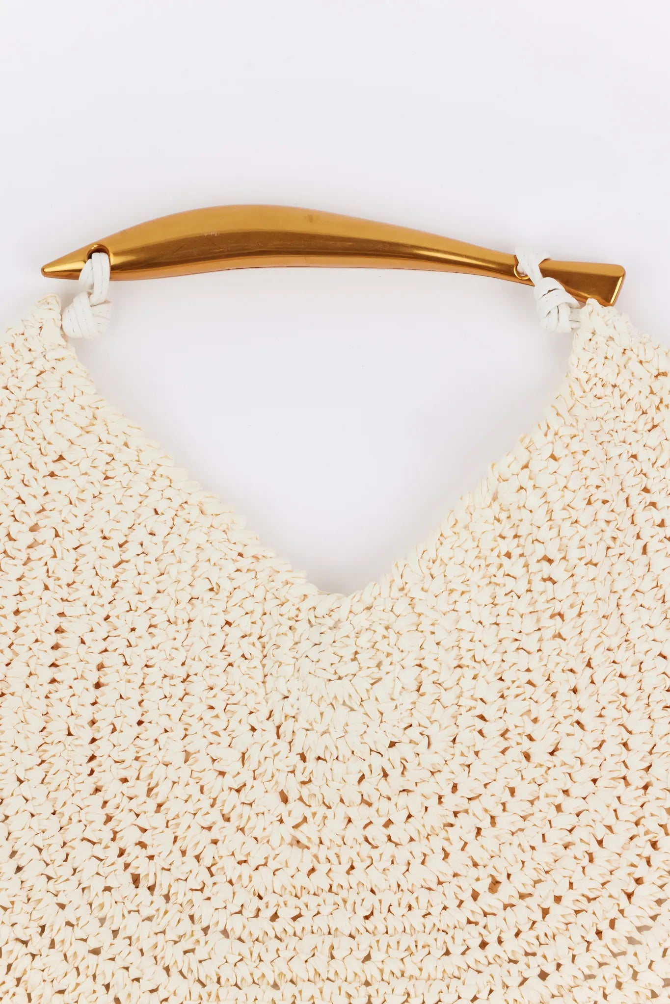 Close-up of the Brielle Bag- Ivory, showcasing its circular woven raffia pattern, gold-metal handle attachment, and spacious slouch style with removable chain.