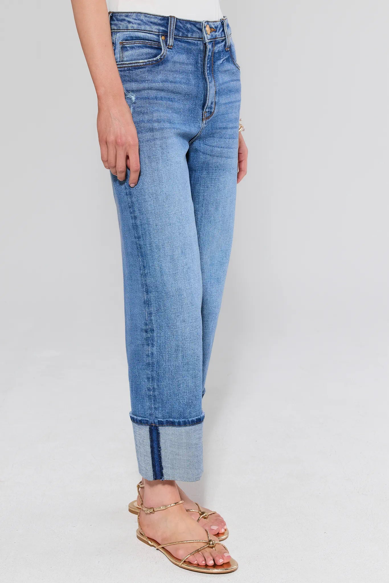 Person wearing blue jeans with a white background and sandals