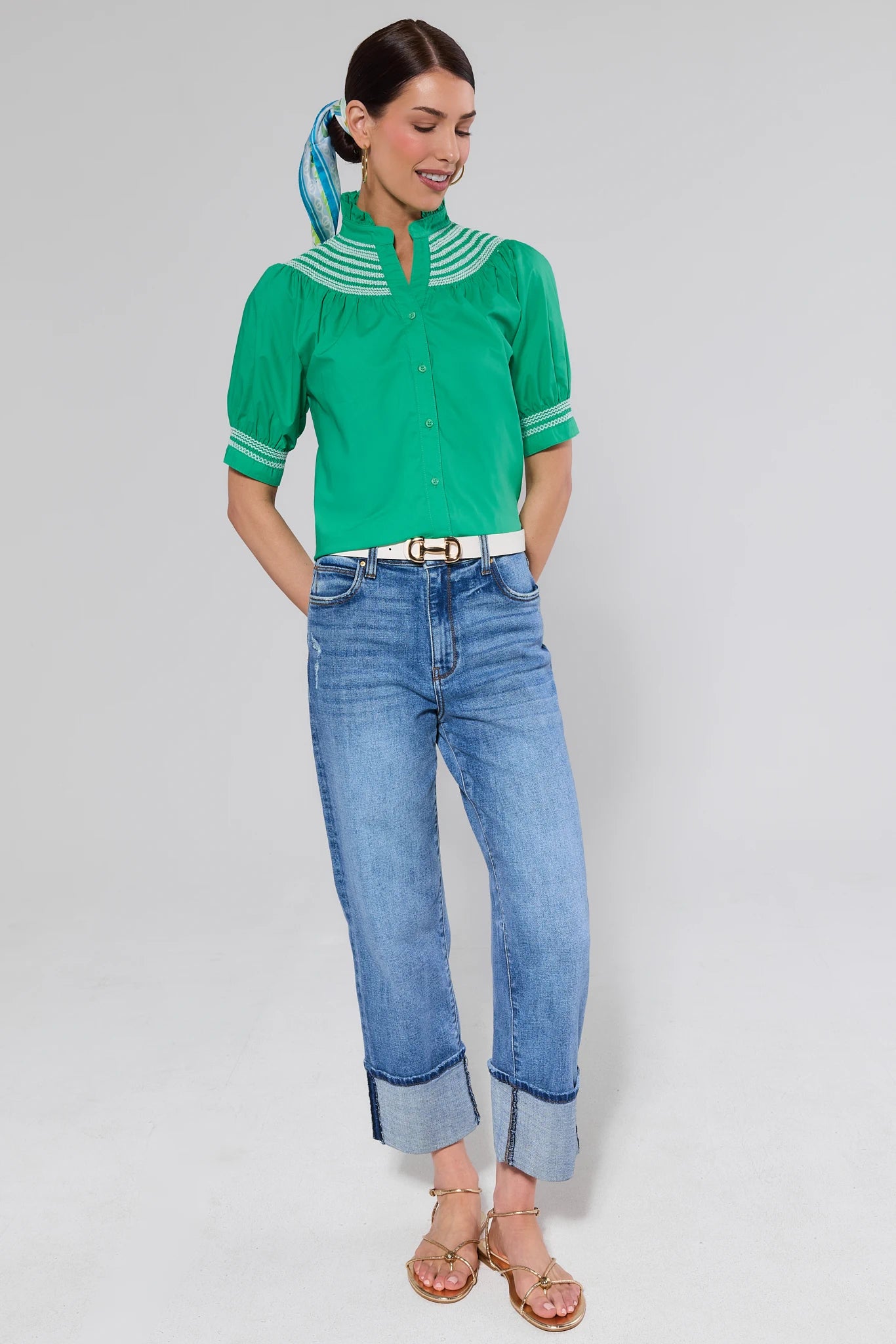 Woman wearing a green blouse and blue jeans on a gray background