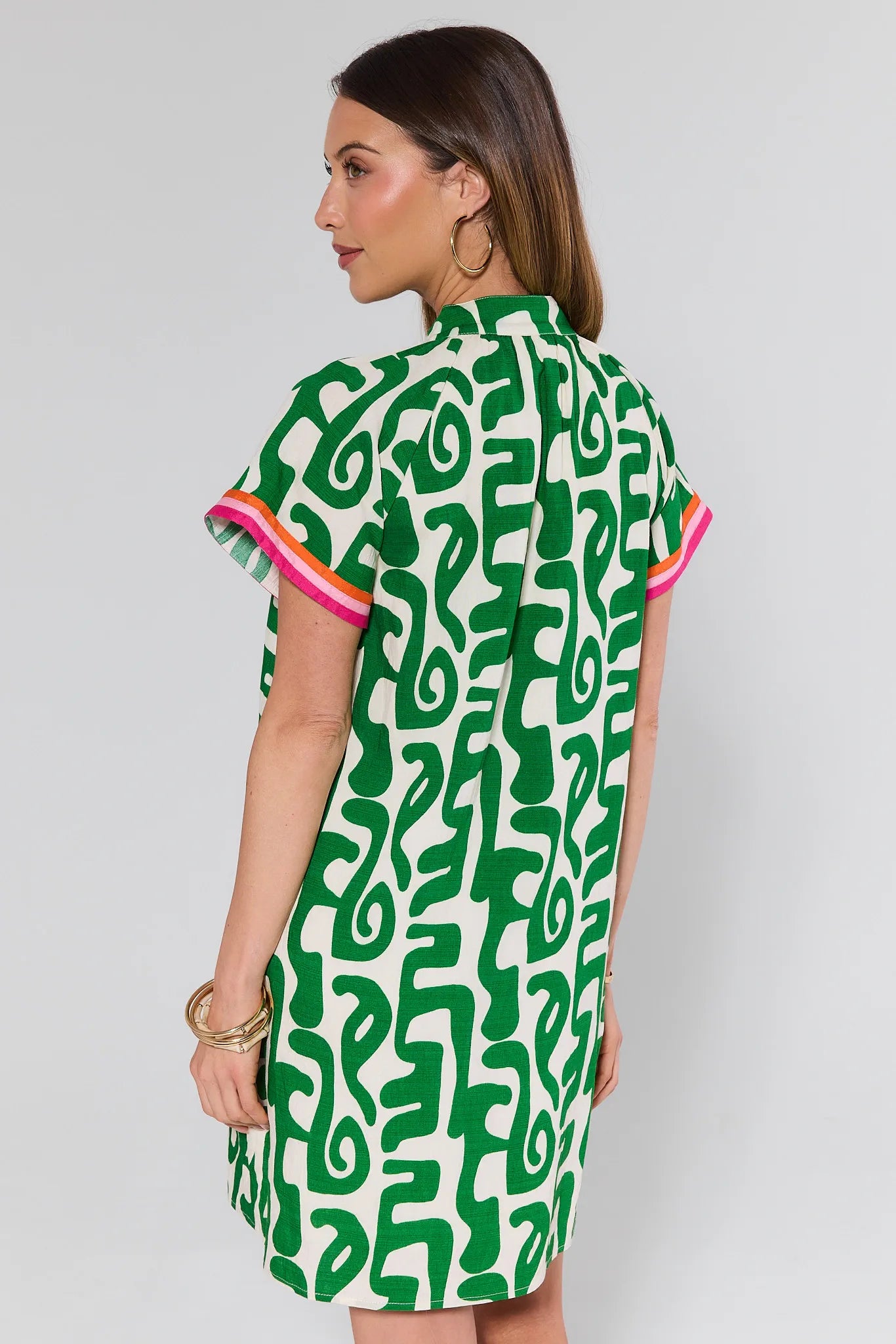 Woman wearing a green and white patterned dress on a plain background