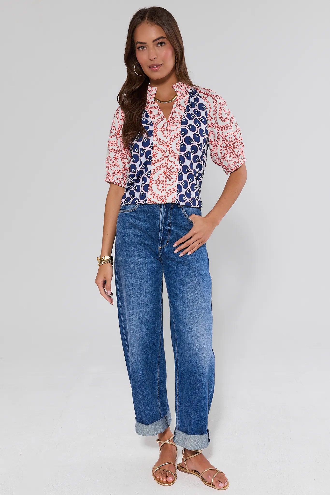 Woman wearing a patterned blouse and blue gigi jeans on a plain background