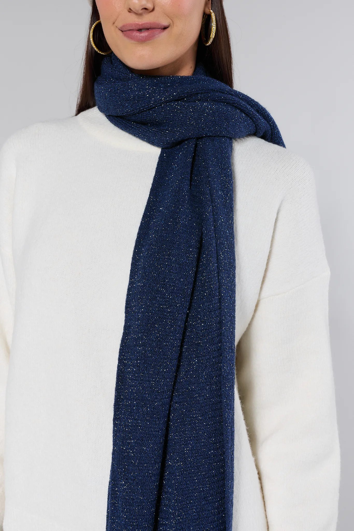 Woman wearing a Karris Navy Fringe Scarf and white top against a gray background