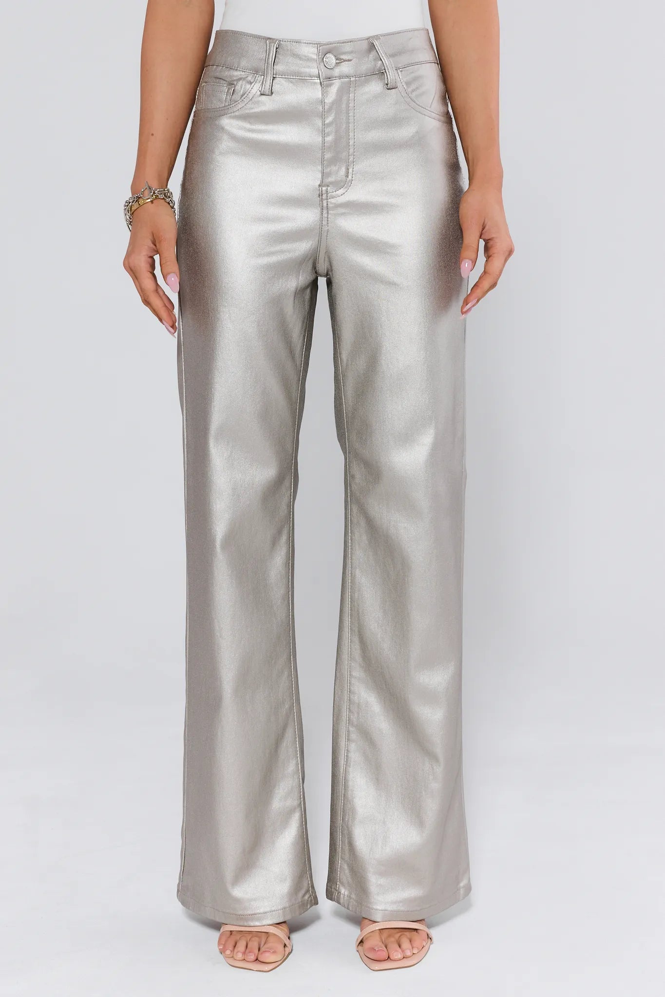 Silver metallic pants worn by a person on a white background