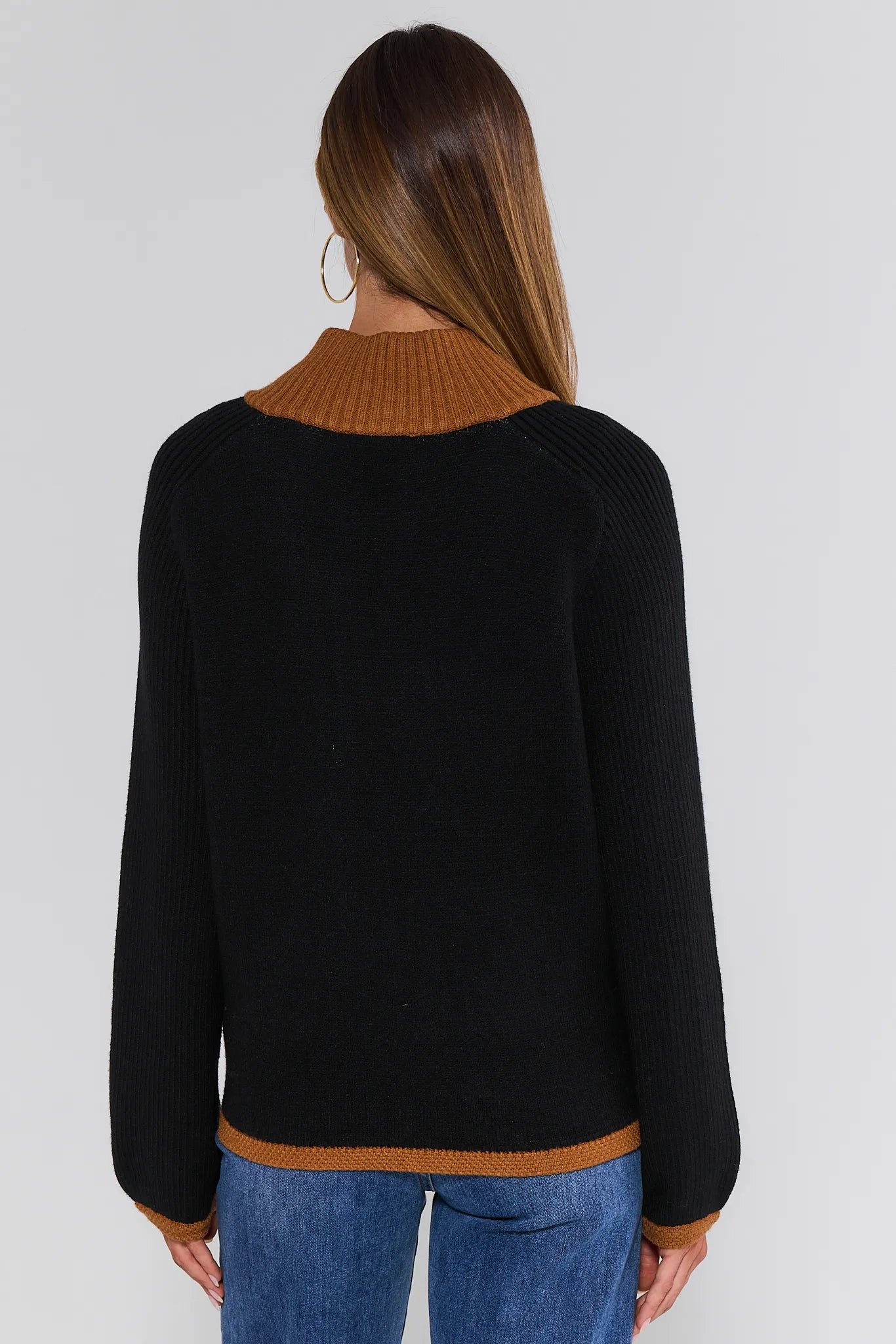 Person wearing a black Cheyenne Cardigan with brown collar and trim on a white background