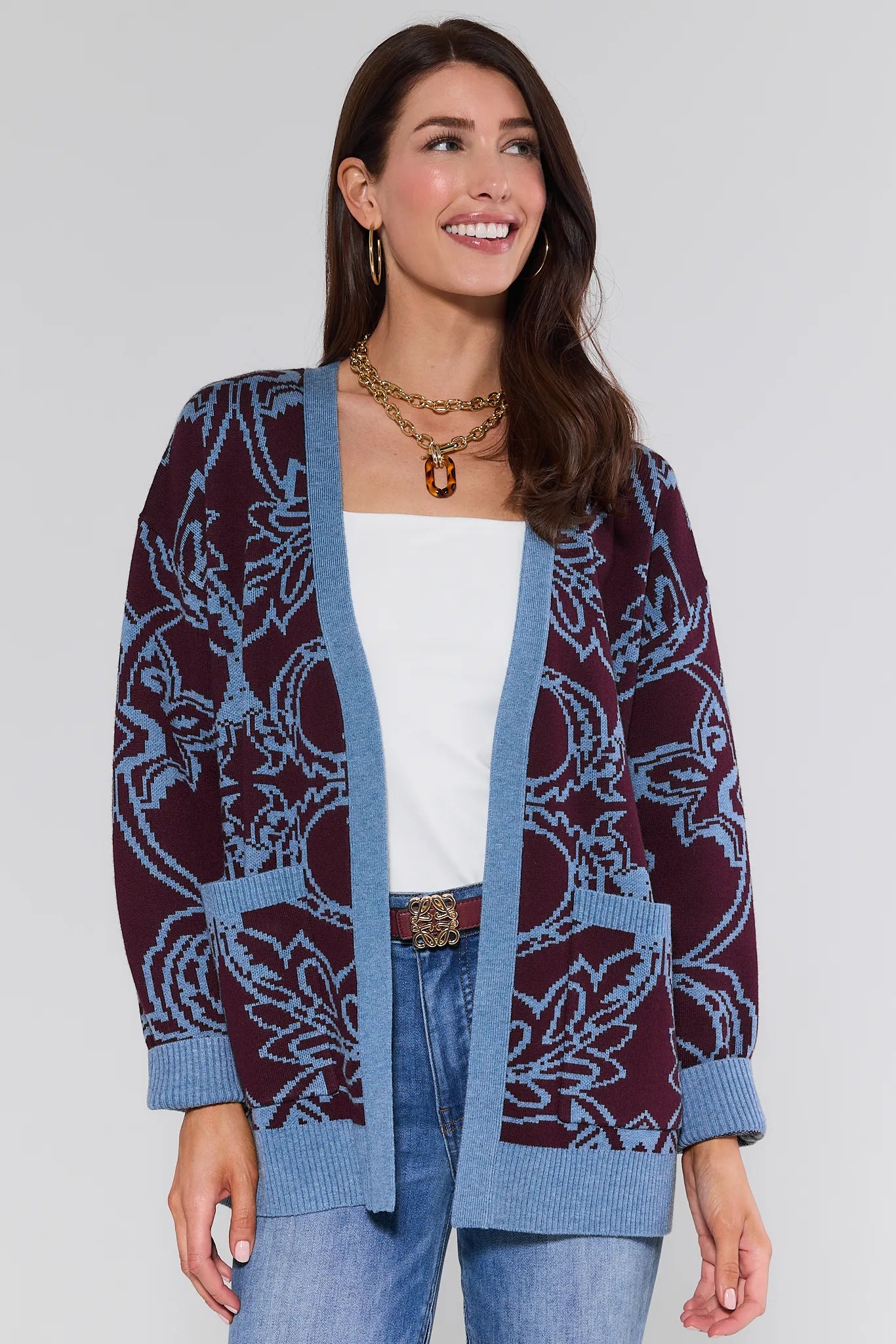 Woman wearing a patterned Liv Cardigan over a white top and blue jeans on a plain background
