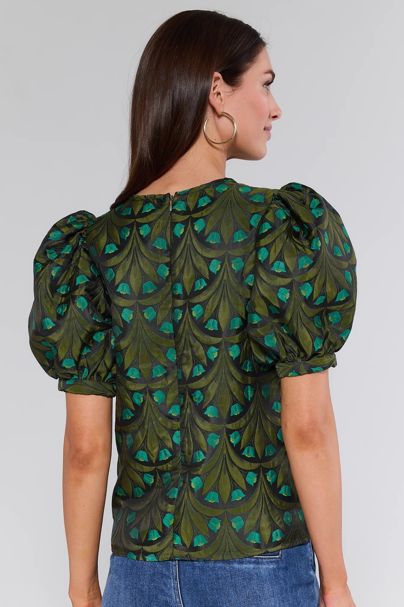 Woman wearing a green patterned Raquel Top with puffed sleeves on a plain background