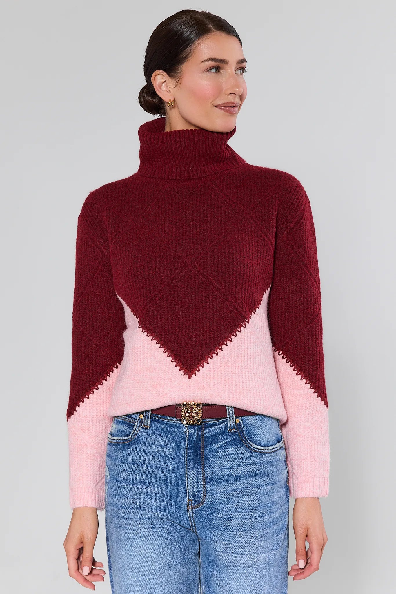 Woman wearing a Bianca Colorblock Turtleneck Sweater maroon and pink with a white background