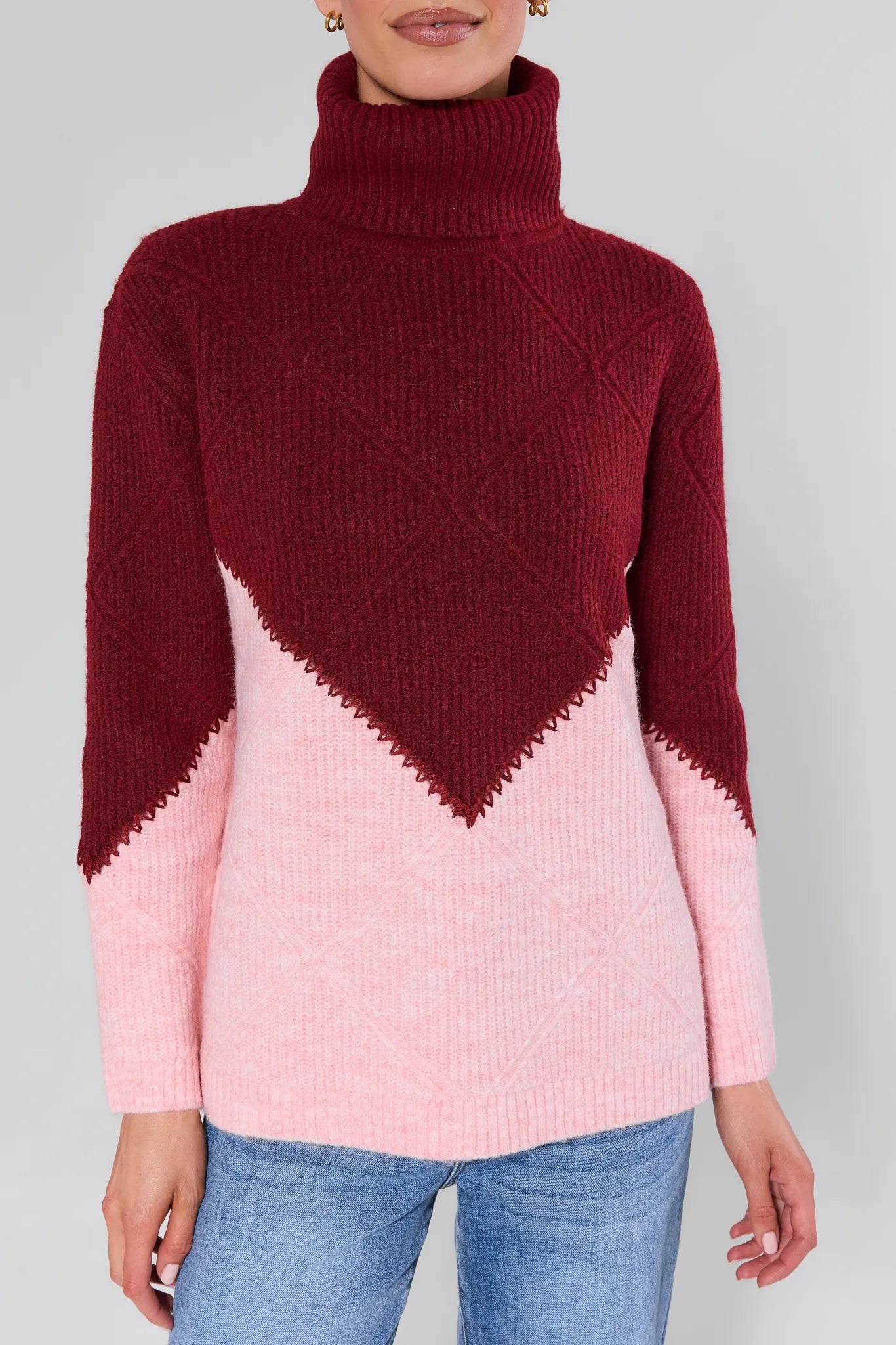 Woman wearing a Bianca Colorblock Turtleneck Sweater maroon and pink with a white background