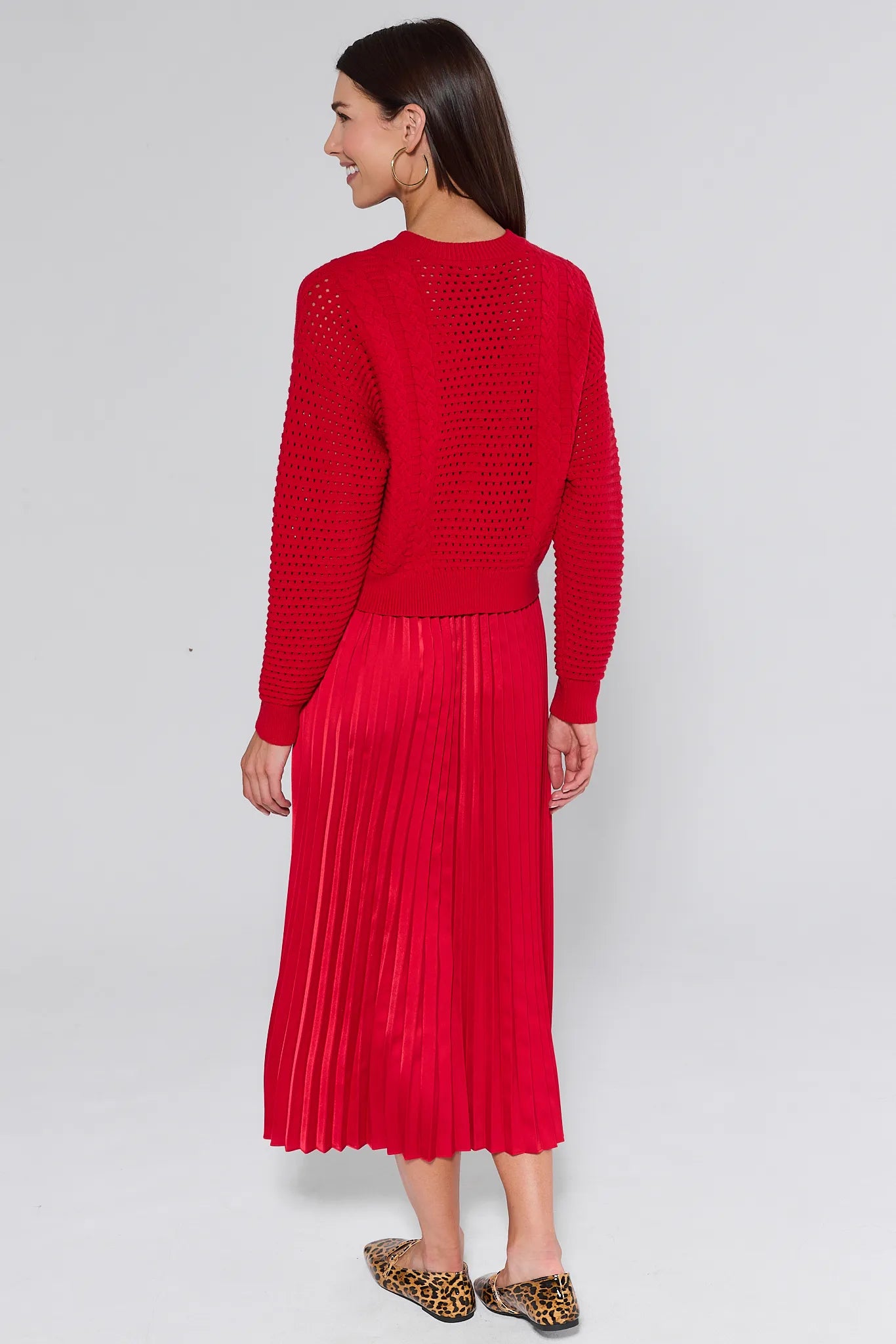 Woman wearing a red knitted and pleated gabbie dress against a white background