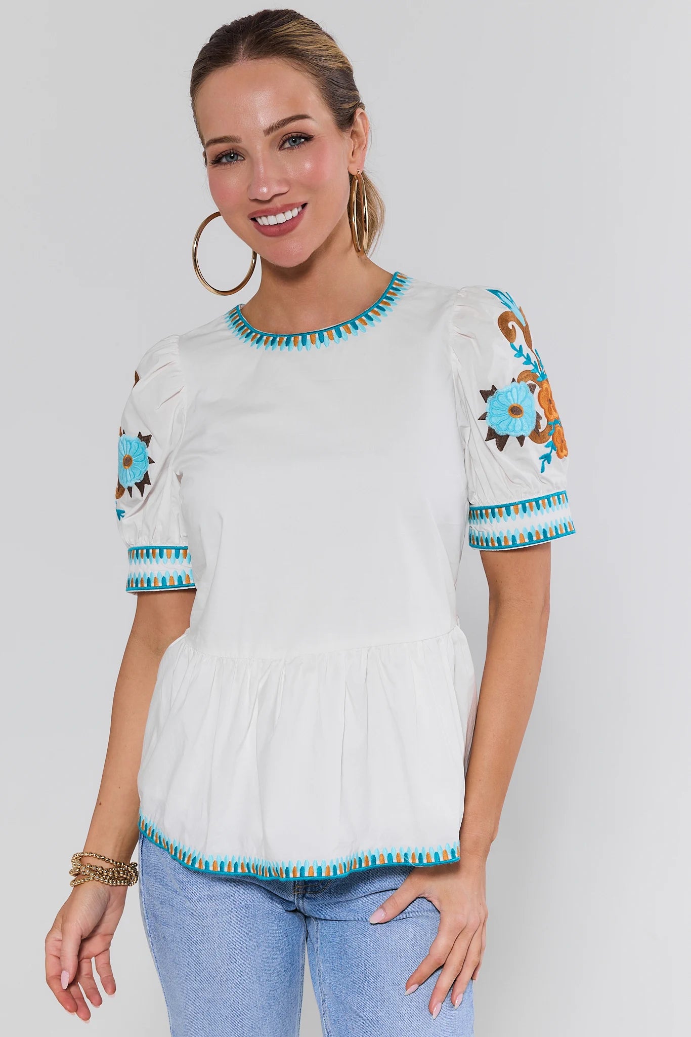 Woman wearing a white blouse with blue floral embroidery on a background