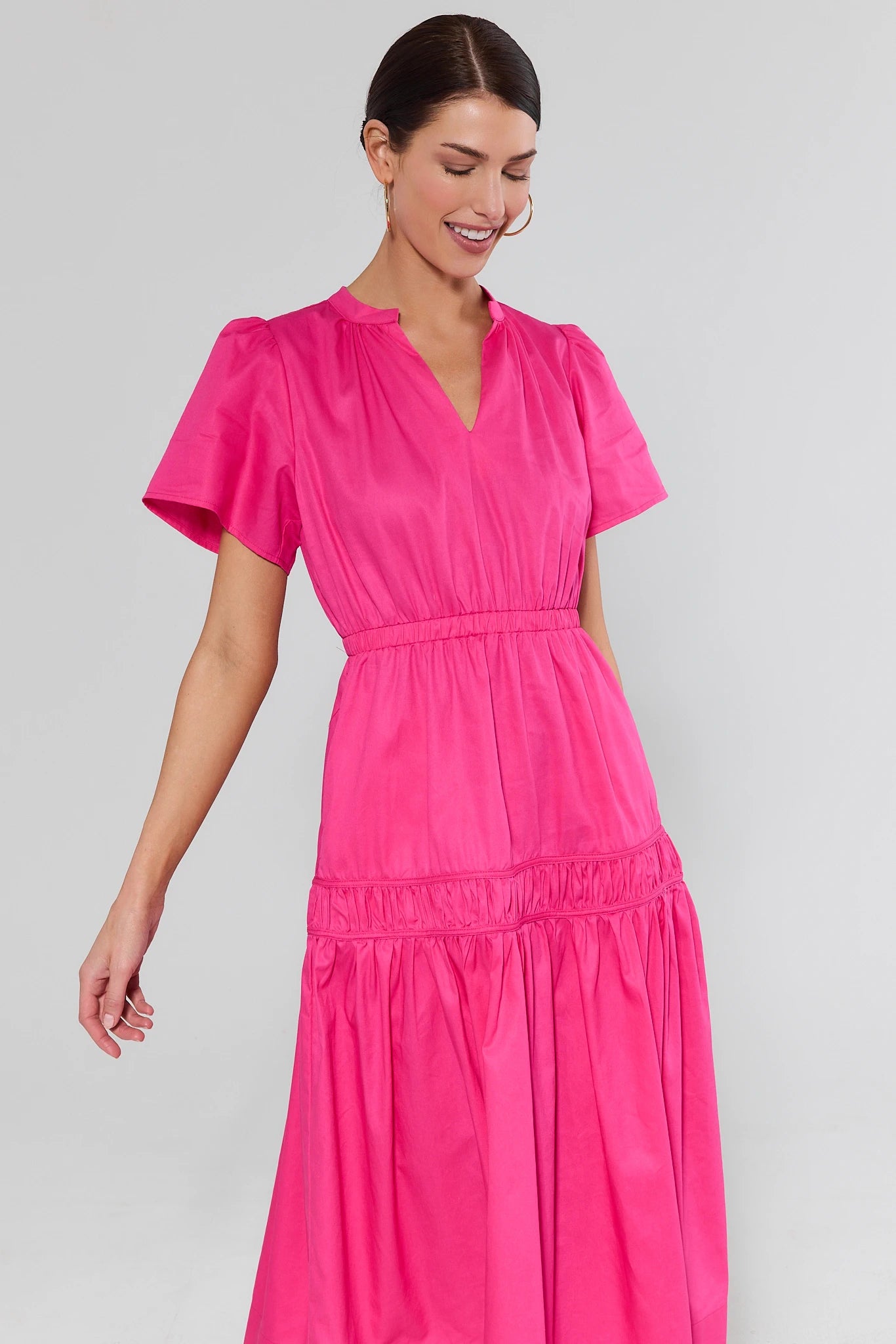 Woman wearing a bright pink dress against a plain background