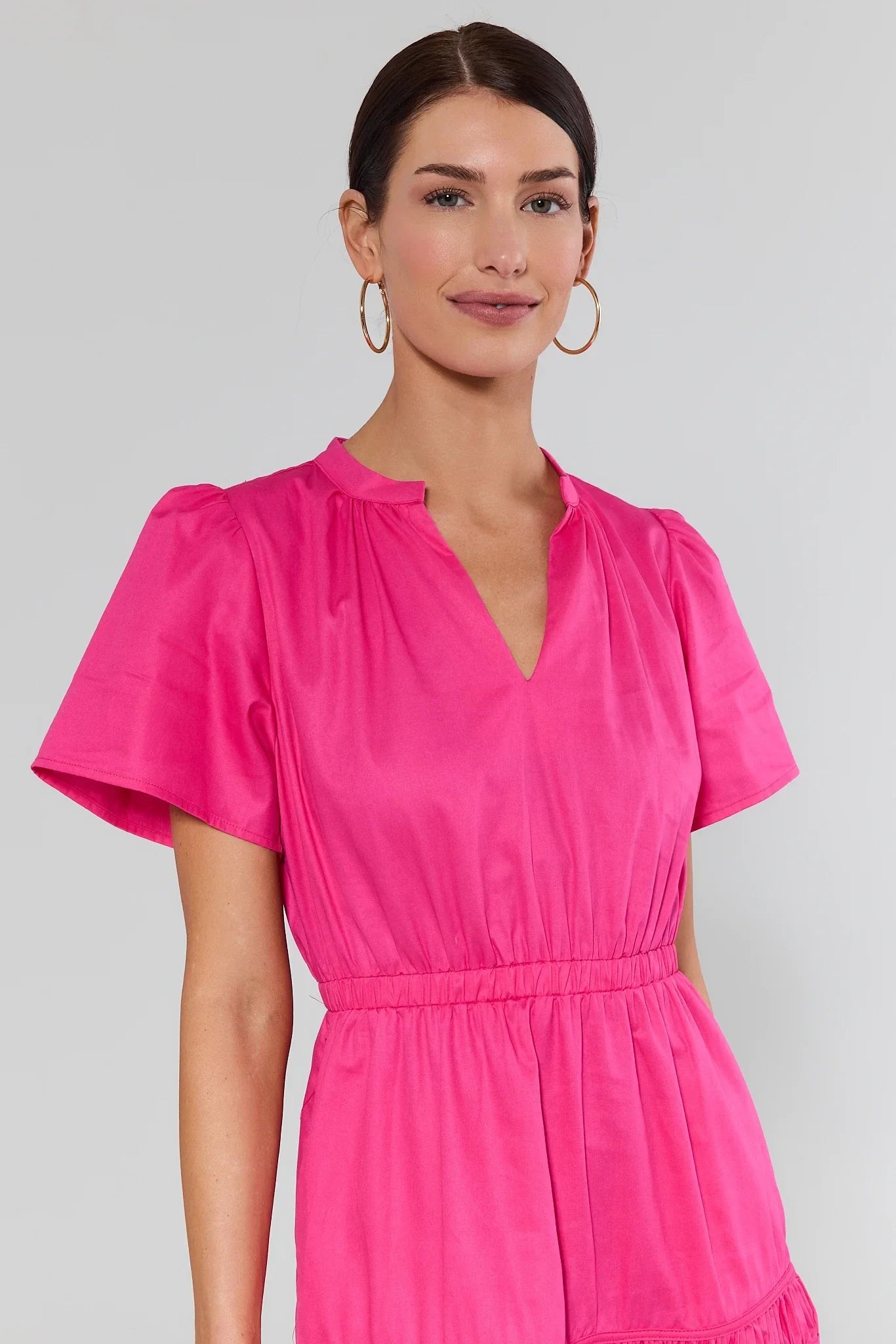 close up of Woman wearing a bright pink dress against a plain background