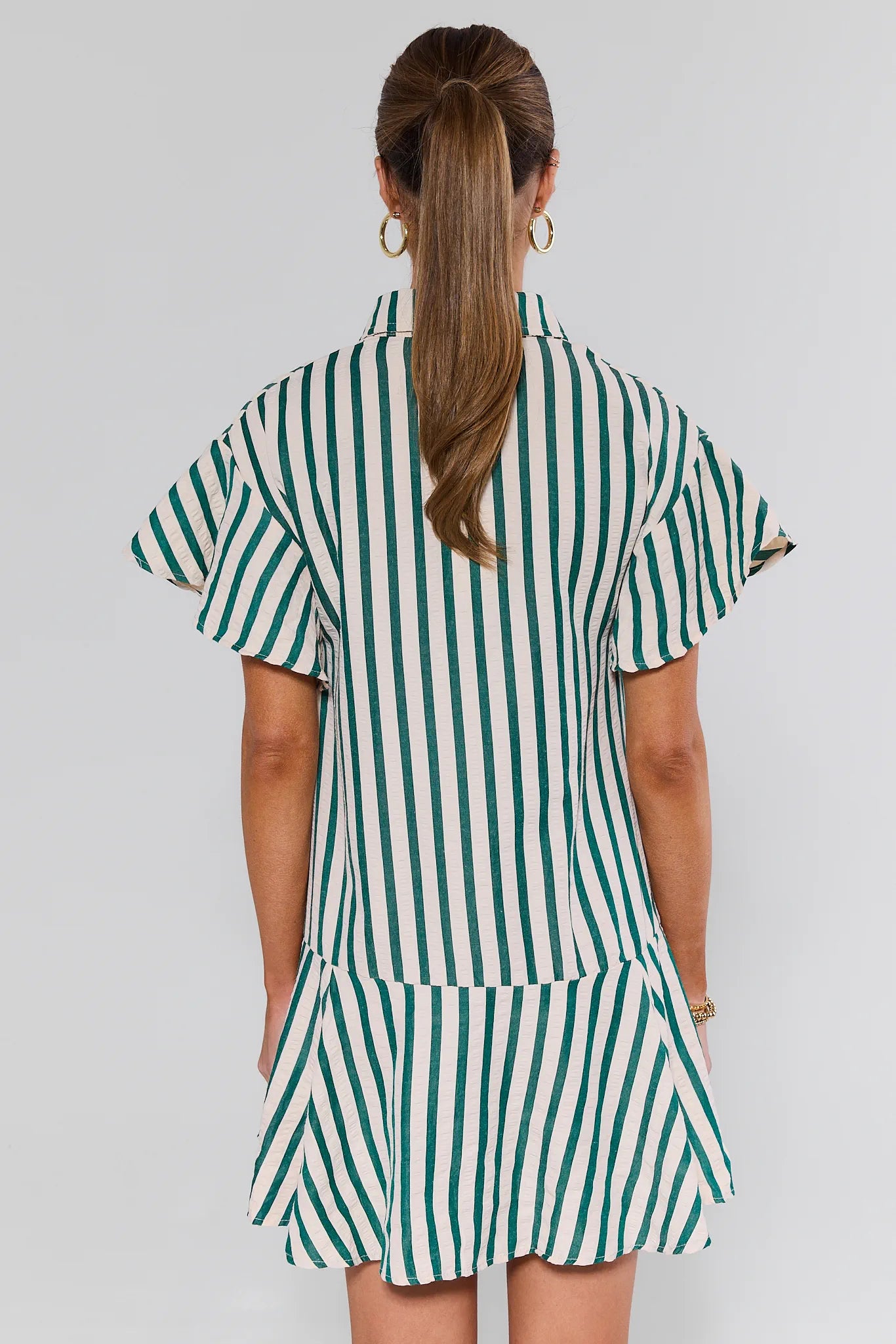 Person wearing a green and white striped dress against a plain background