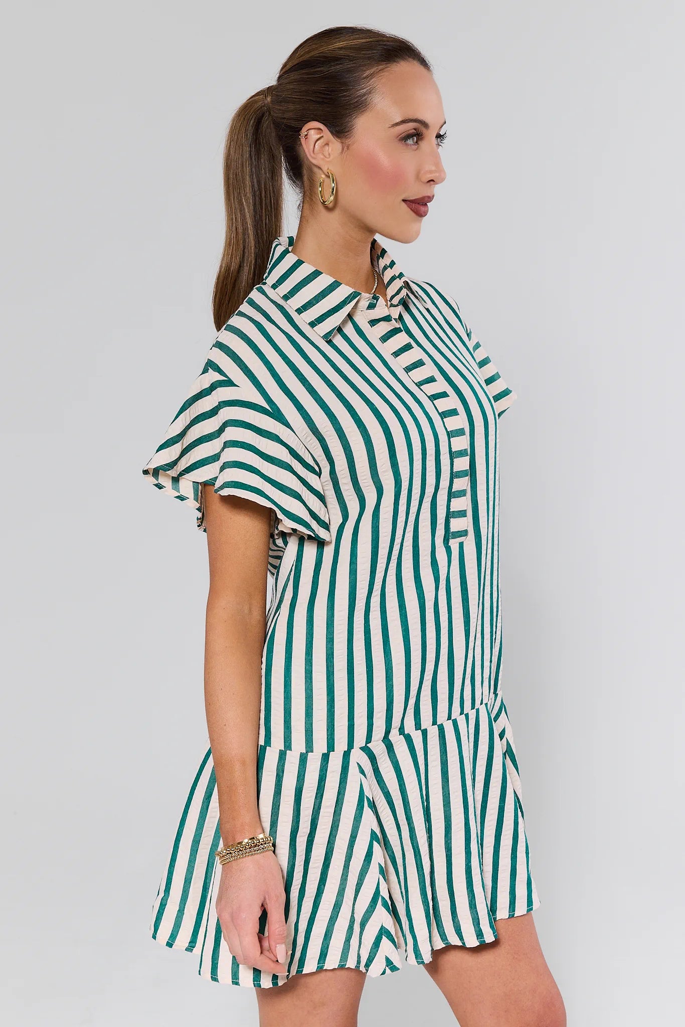 Woman wearing a green and white striped dress against a plain background