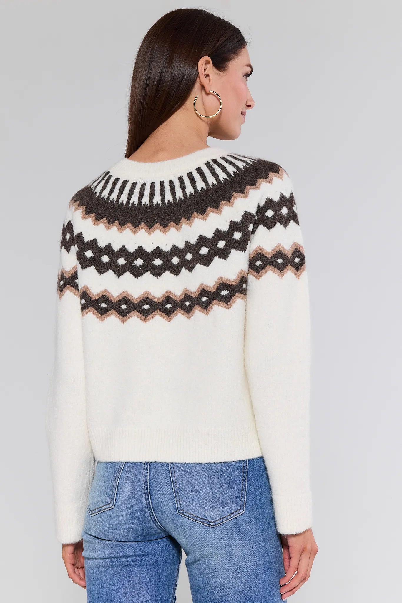 Woman wearing a patterned Marianne Sweater and jeans on a plain background