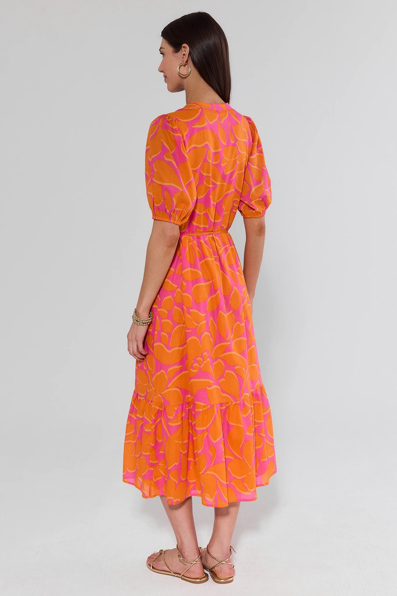 Woman wearing an orange and pink patterned dress on a white background