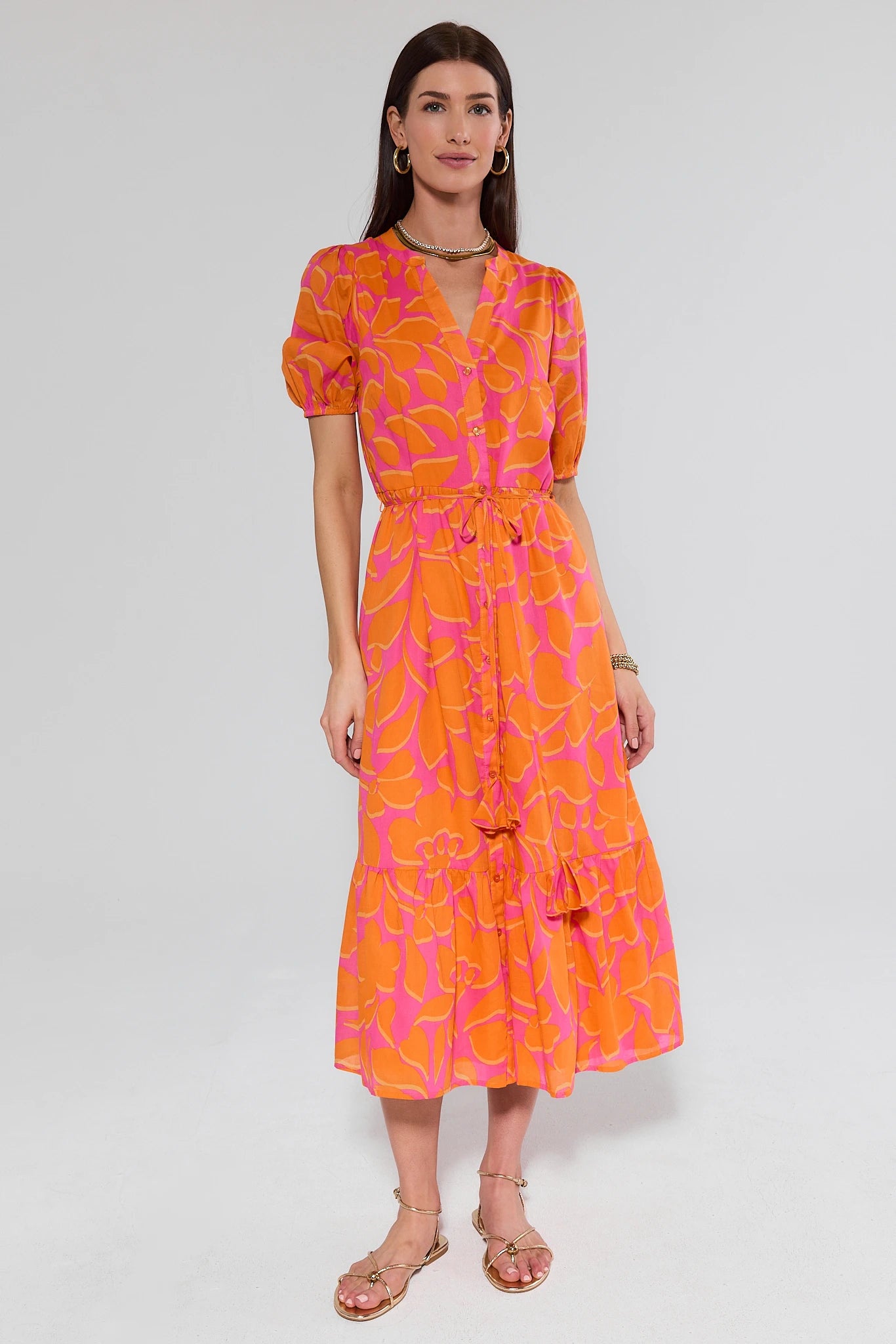 Woman wearing an orange and pink patterned dress on a white background