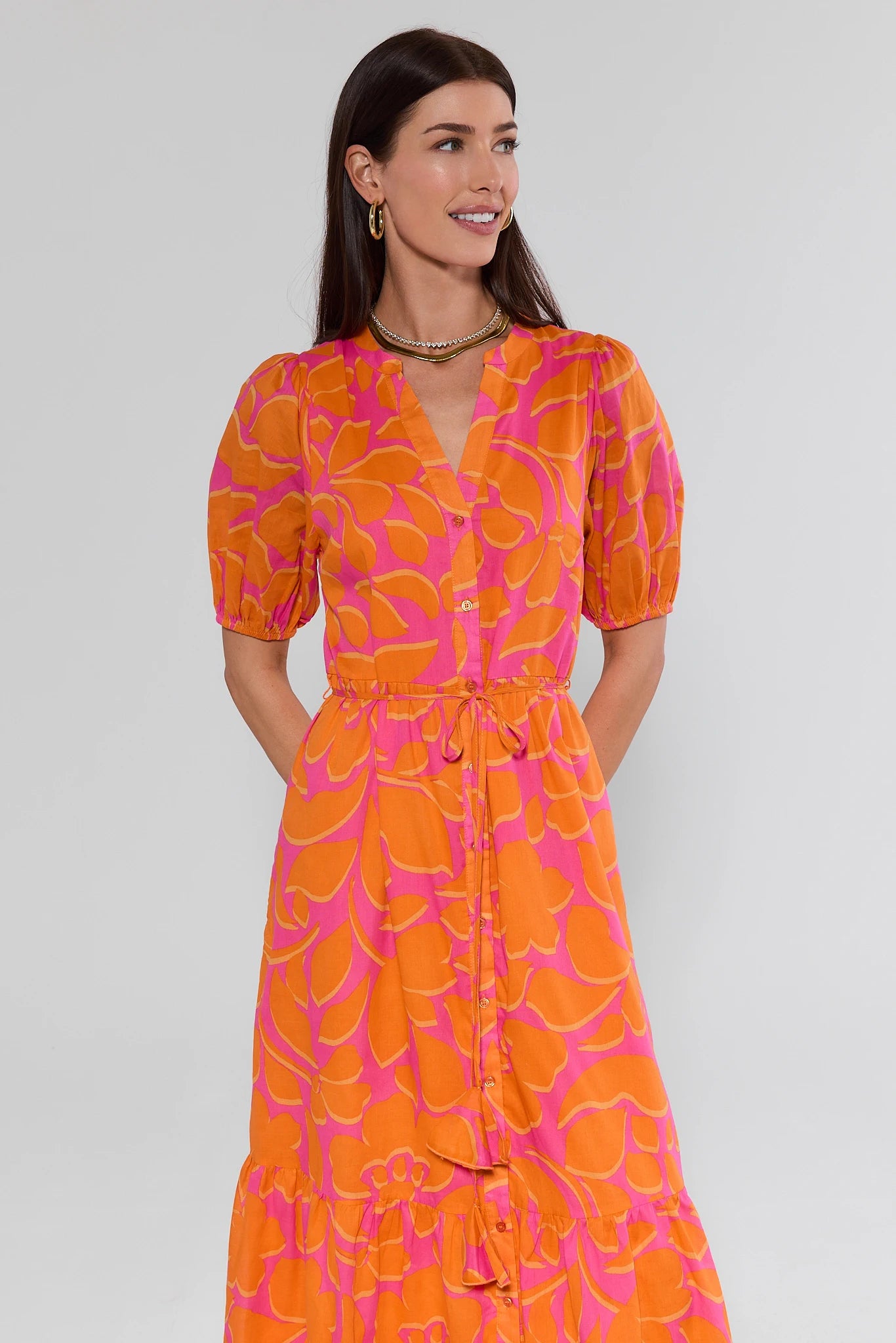 Woman wearing an orange and pink patterned dress against a white background