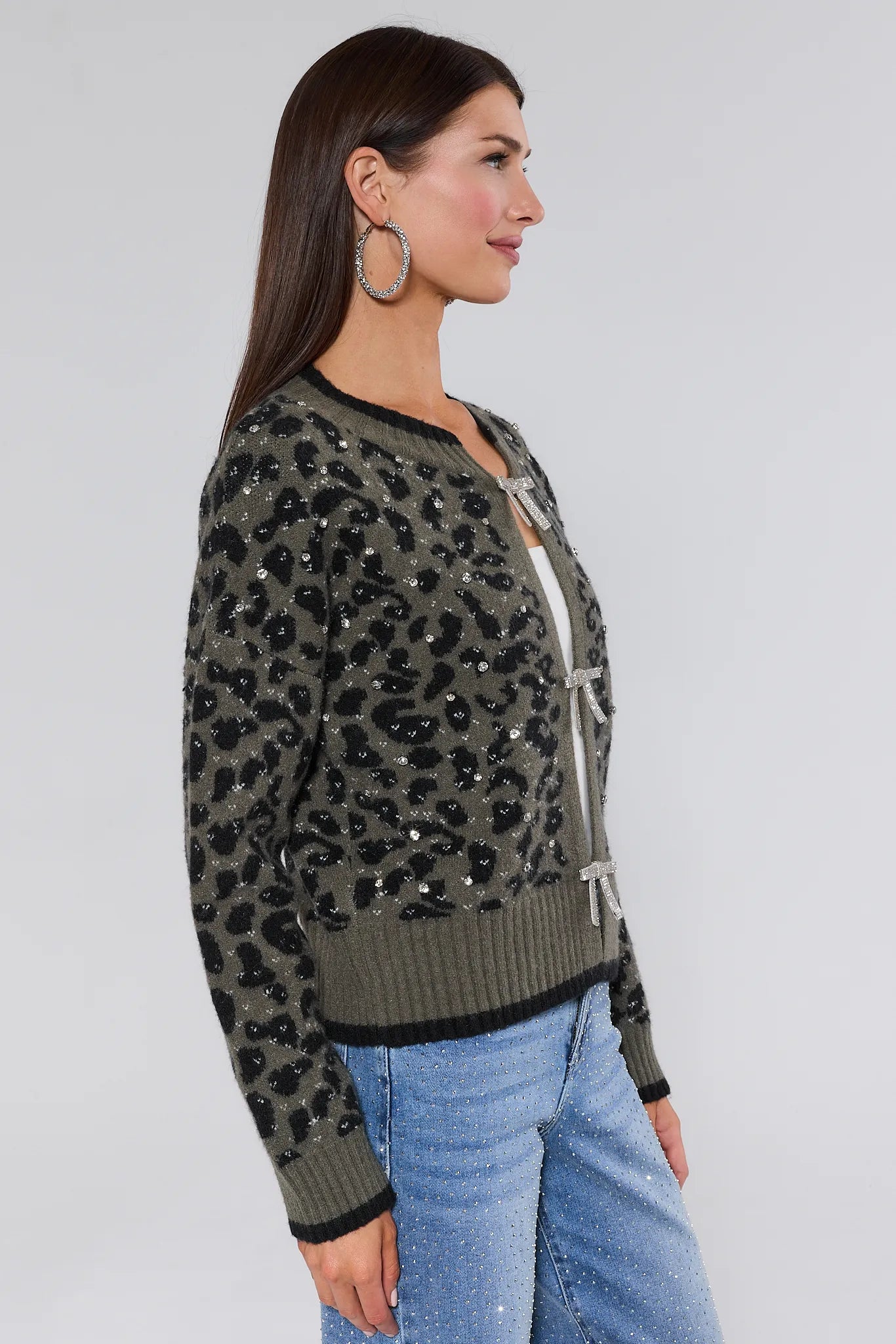 Woman wearing a leopard print marcie sweater with sequins and blue jeans on a white background