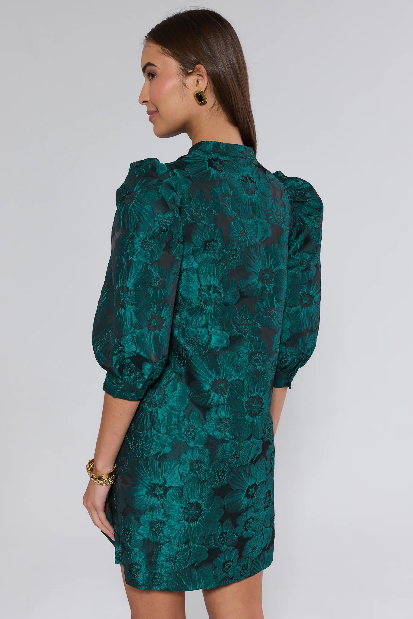 Woman wearing a green floral dress against a white background