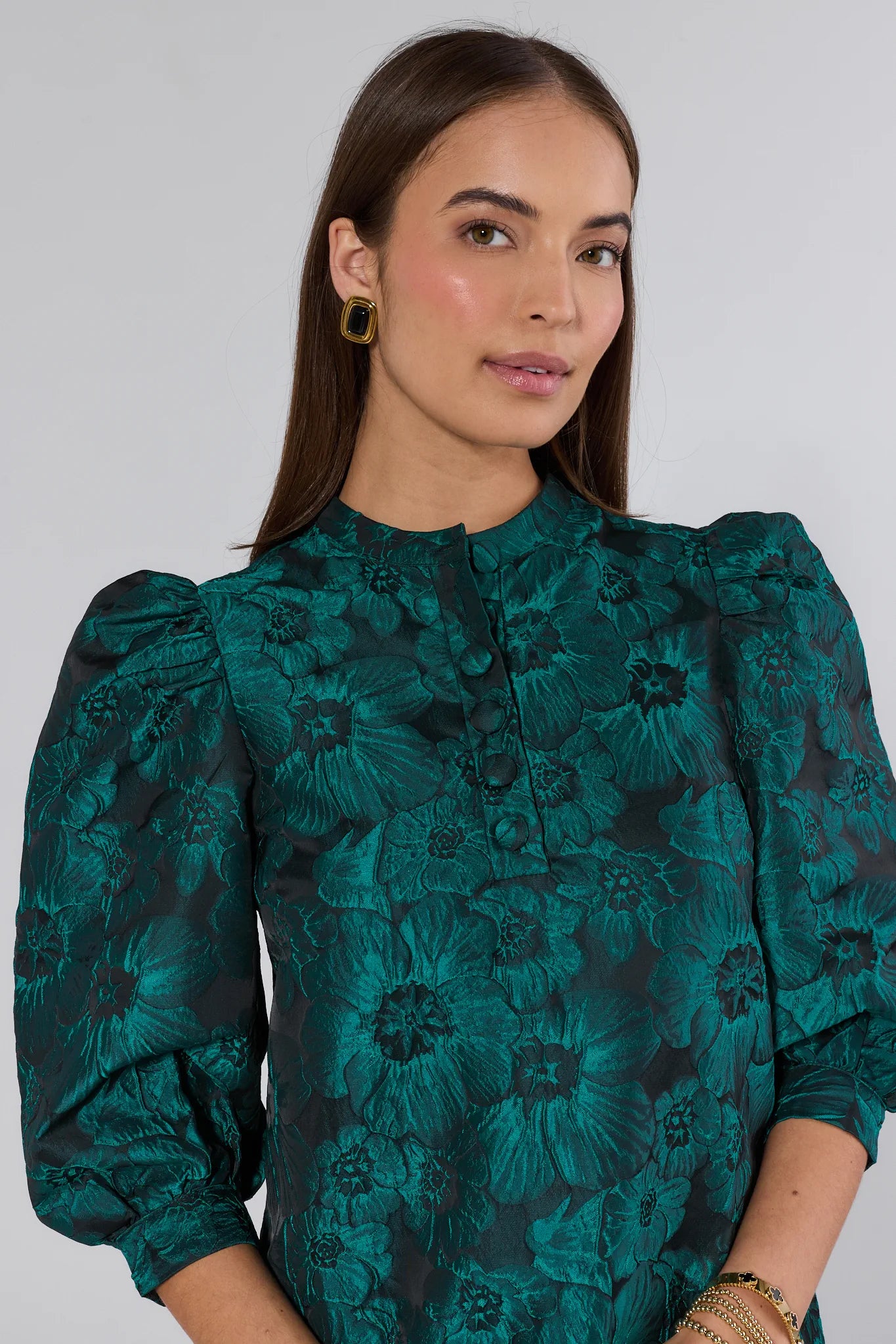 Woman wearing a green floral dress against a plain background