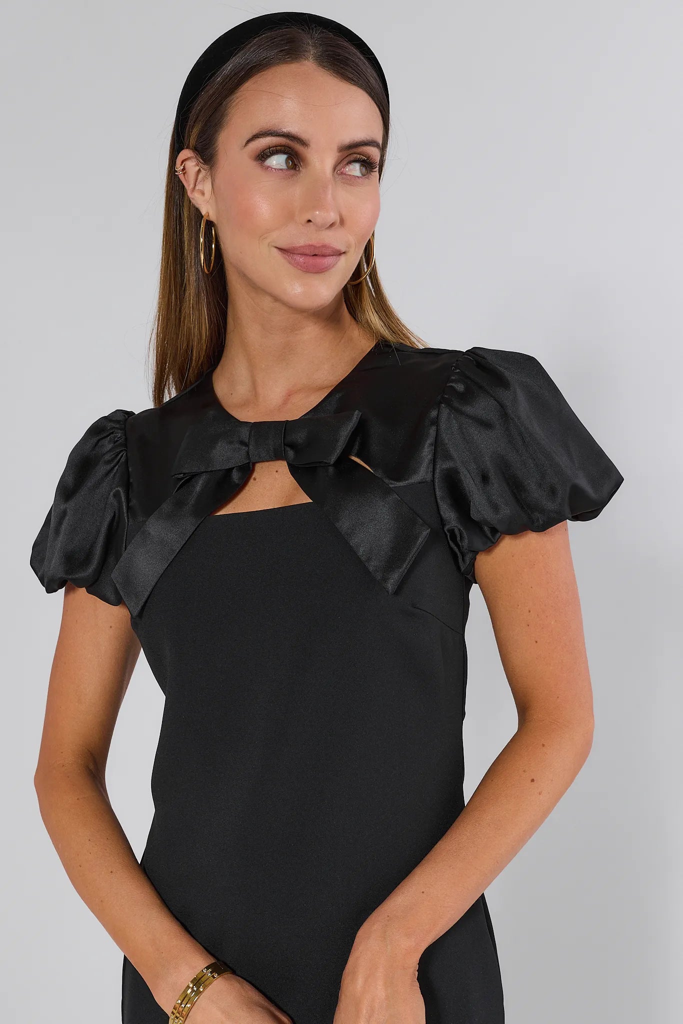 Black Anna dress with ruffled sleeves and a bow detail on a plain background